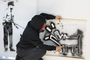 Die Performerin Cornelia Kupferschmid sprüht die Konturen eines Banksy-Hundes auf eine Leinwand.