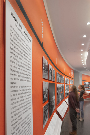 Zwei Besucherinnen im Ausstellungsraum. Im Vordergrund ist die Texttafel zur Ausstellung zu sehen