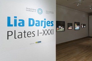 Der Eingang zum Ausstellungsraum mit dem Titel der Ausstellung auf der linken Wand. Im Hintergrund sind die Arbeiten der Fotografin zu sehen.