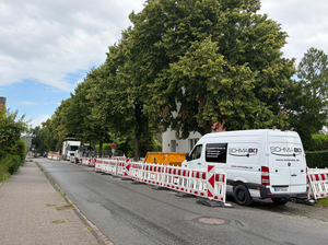 Zu sehen ist die Schmeddingstraße, die auf der rechten Fahrbahnseite komplett mit Baustellenbaken und Baustellenfahrzeugen abgesperrt ist.