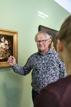 Der Ausstellungsmacher steht vor einem Gemälde von Elise Michelis.