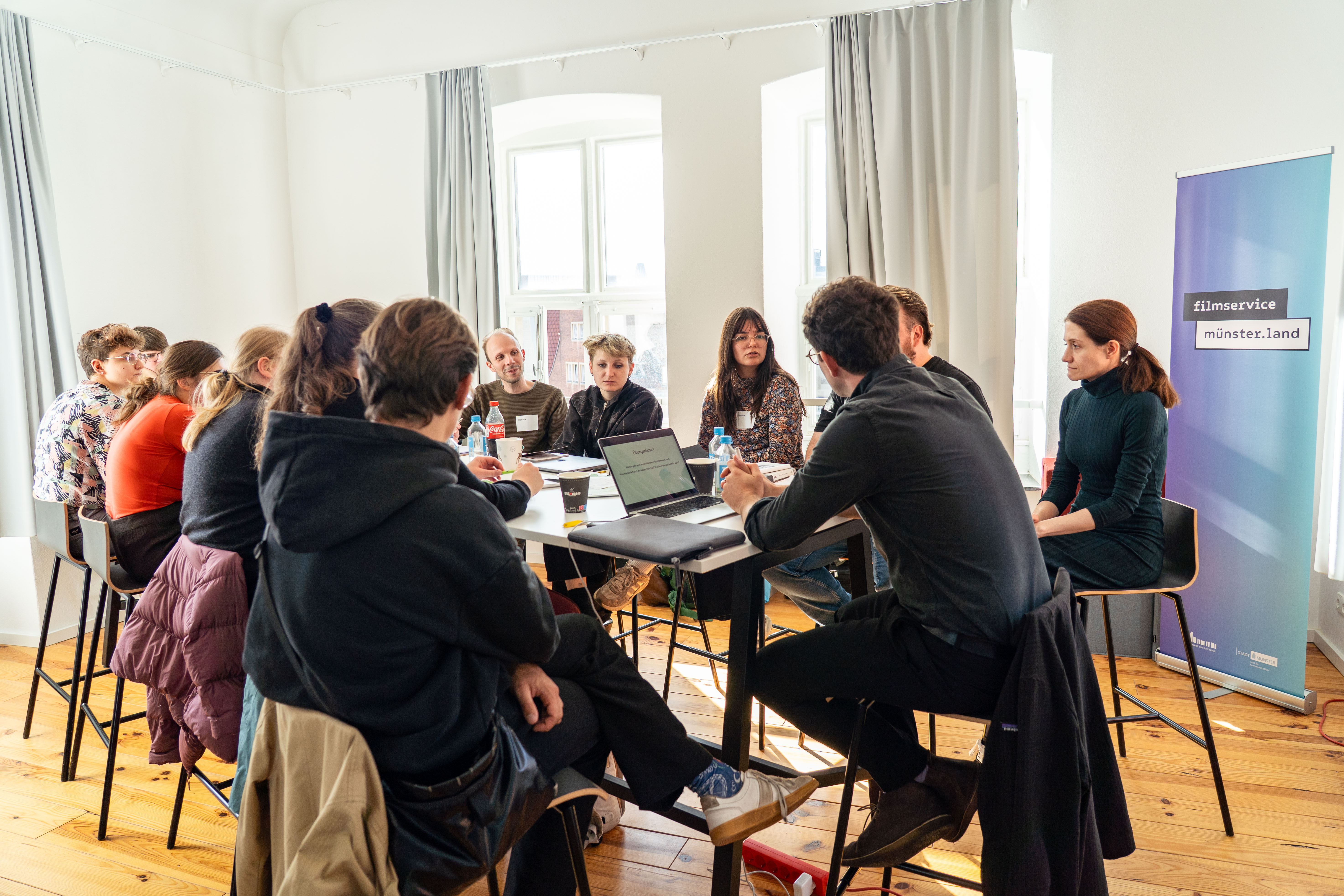 Workshopteilnehmende aus Film und Literatur sitzen am Tisch