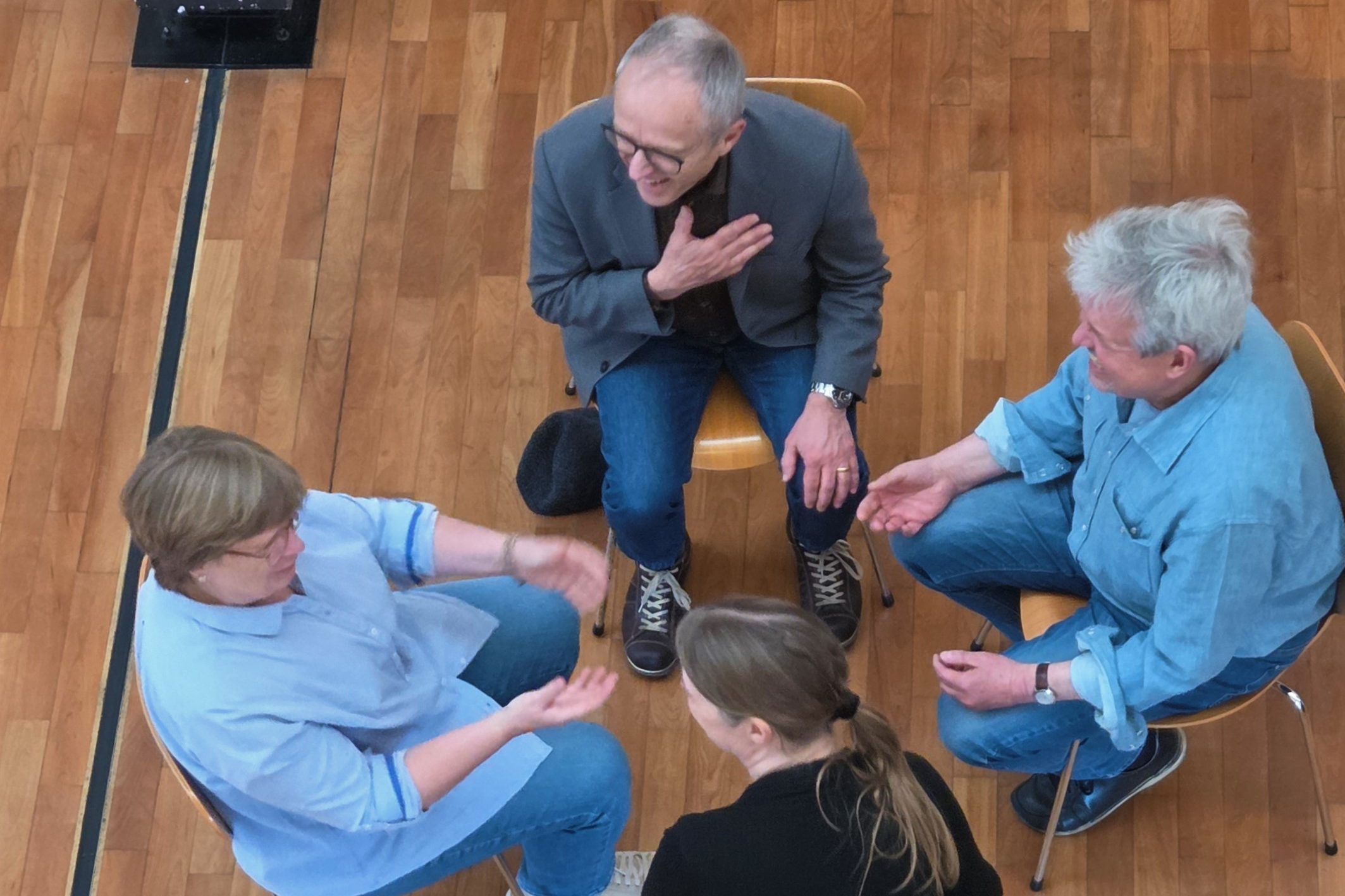 Vier Menschen sitzen sich gegenüber und sprechen miteinander.
