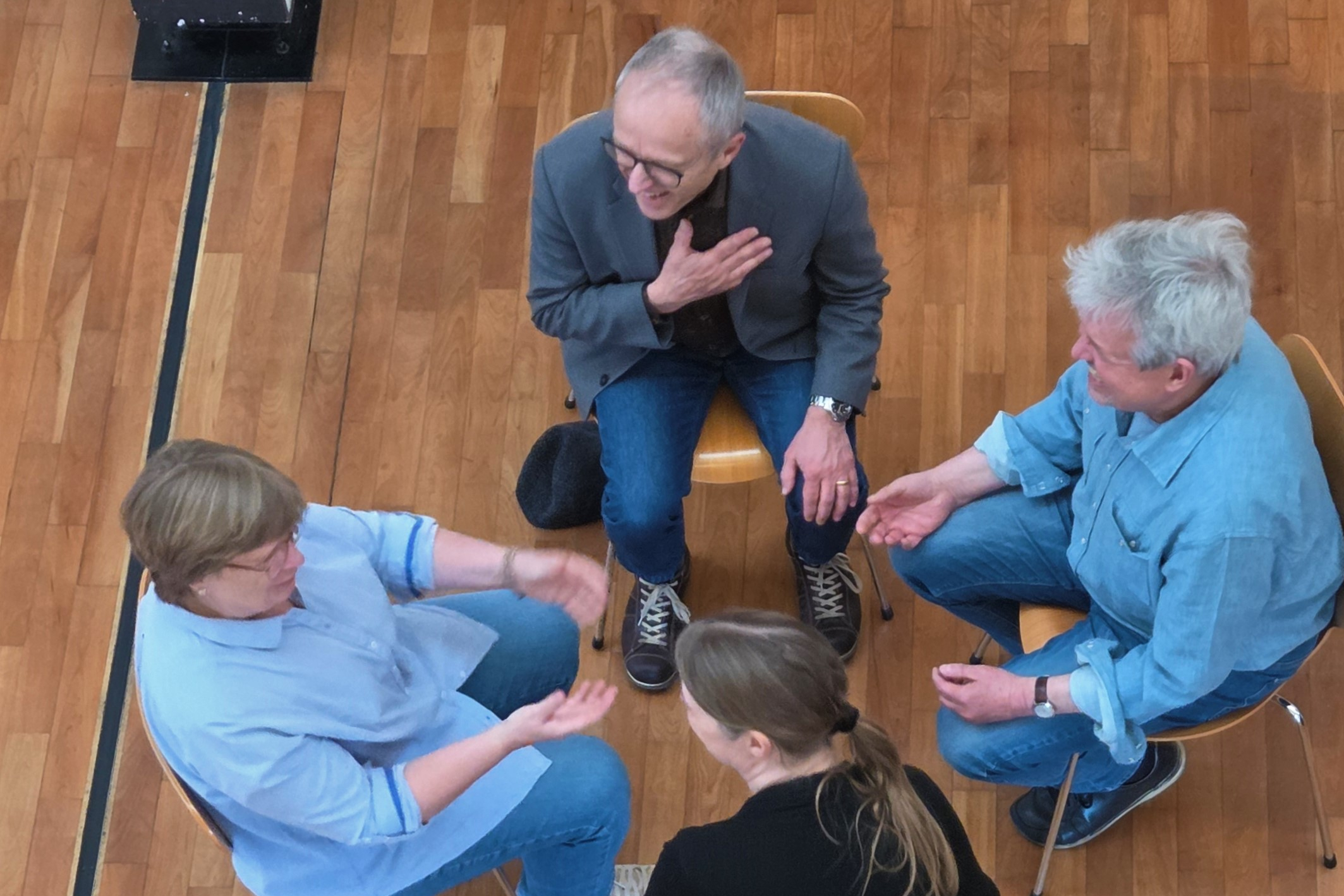 Vier Menschen sitzen sich gegenüber und sprechen miteinander.
