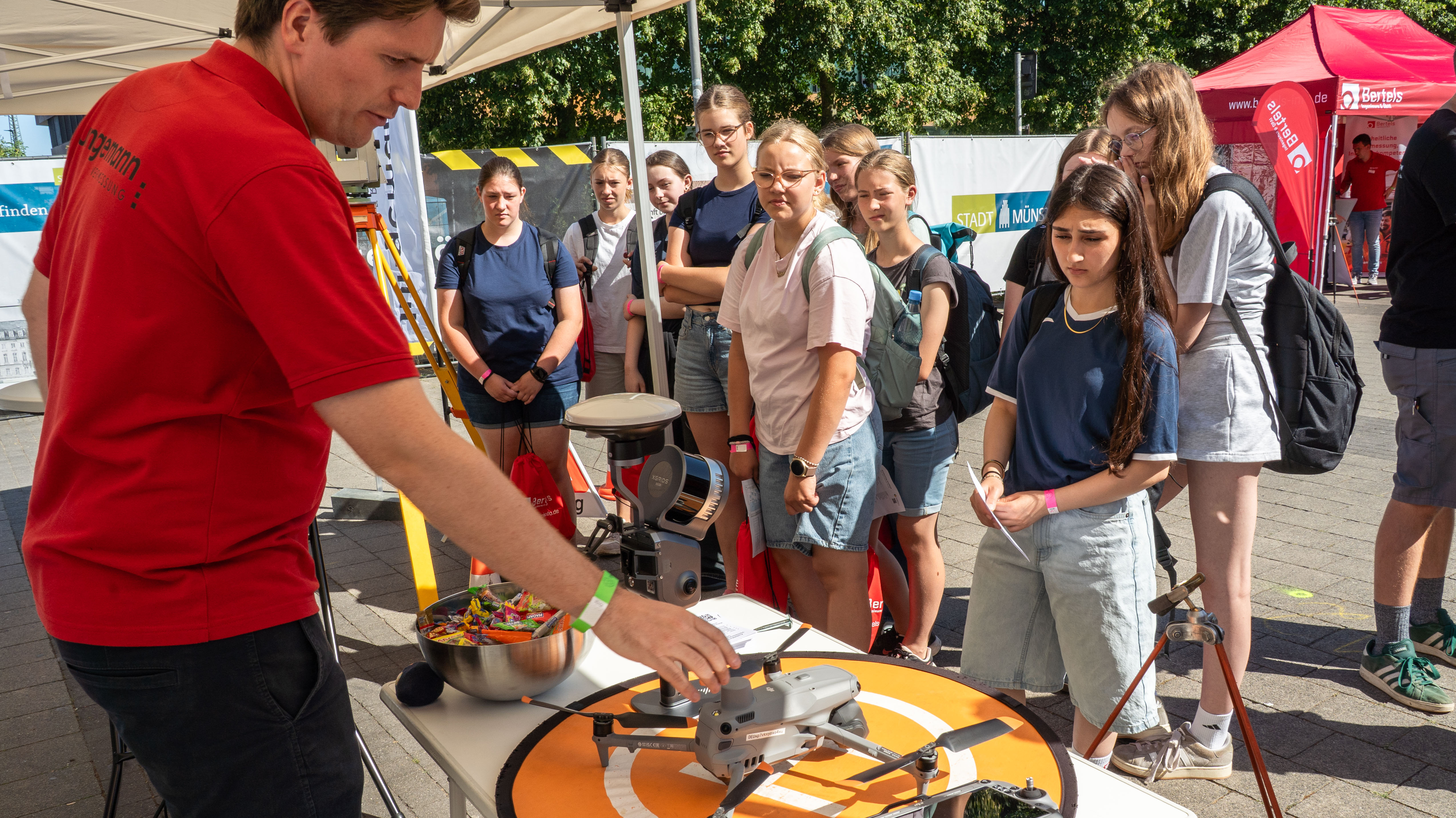 Junge Leute stehen vor einem Informationsstand mit einer Drohne.