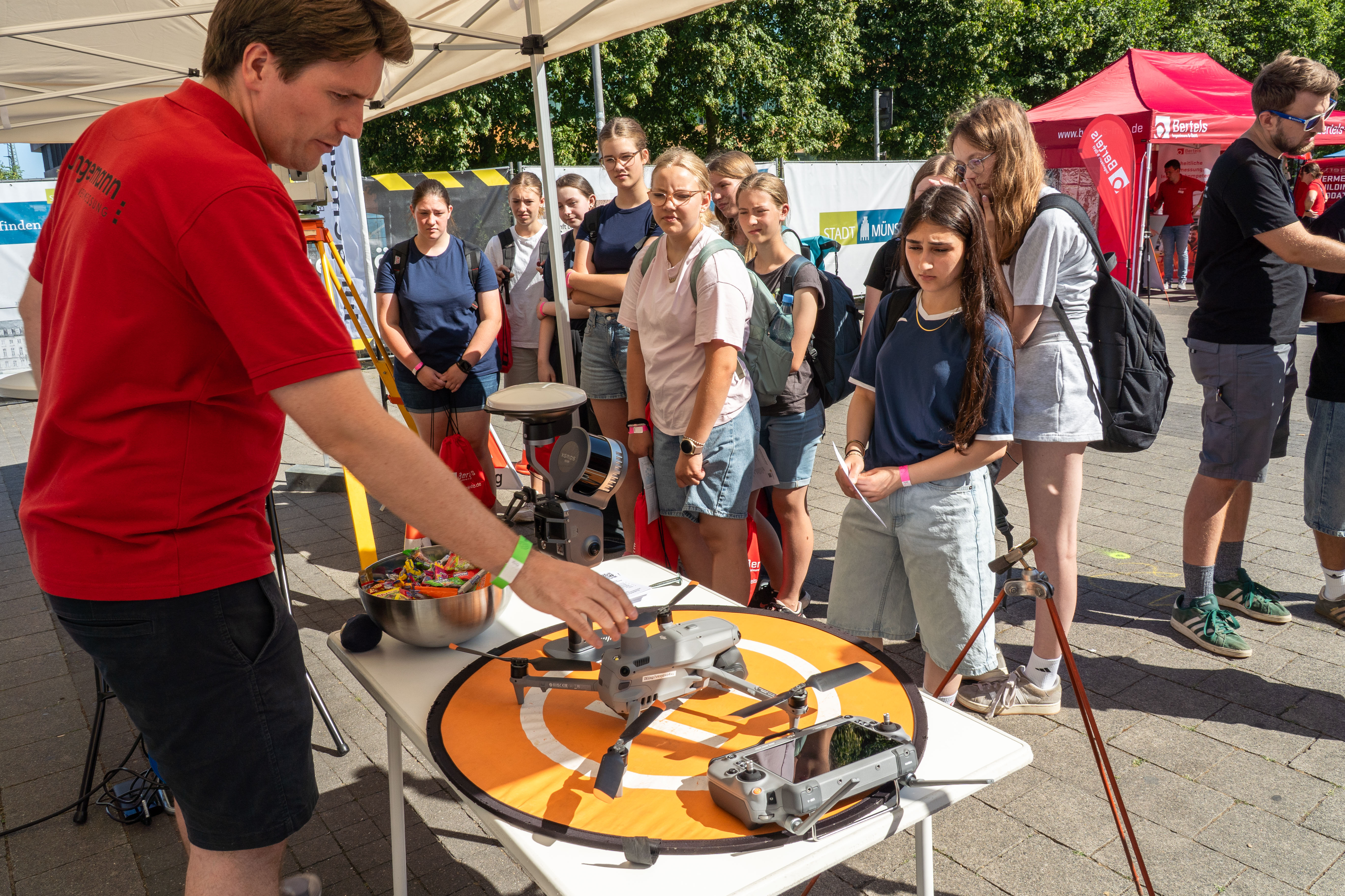 Junge Leute stehen vor einem Informationsstand mit einer Drohne.