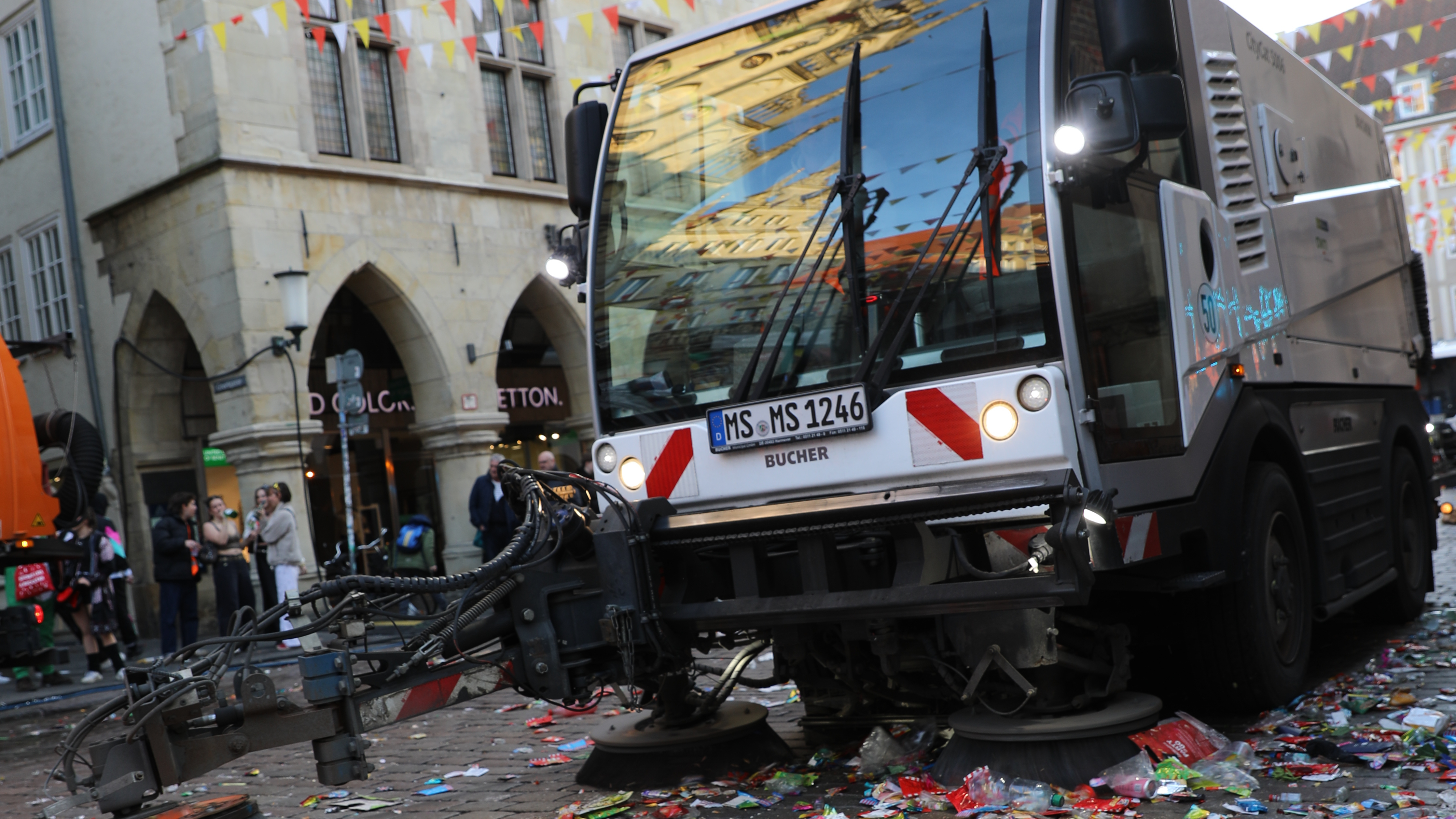 Abfall auf der Straße und ein Entsorgungsfahrzeug in Arbeit