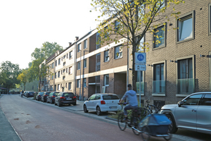 Foto der roten Fahrradstraße Wilhelmstraße inkl. Beschilderung, im Vordergrund sieht man einen Menschen mit Kinderanhänger Fahrrad fahren