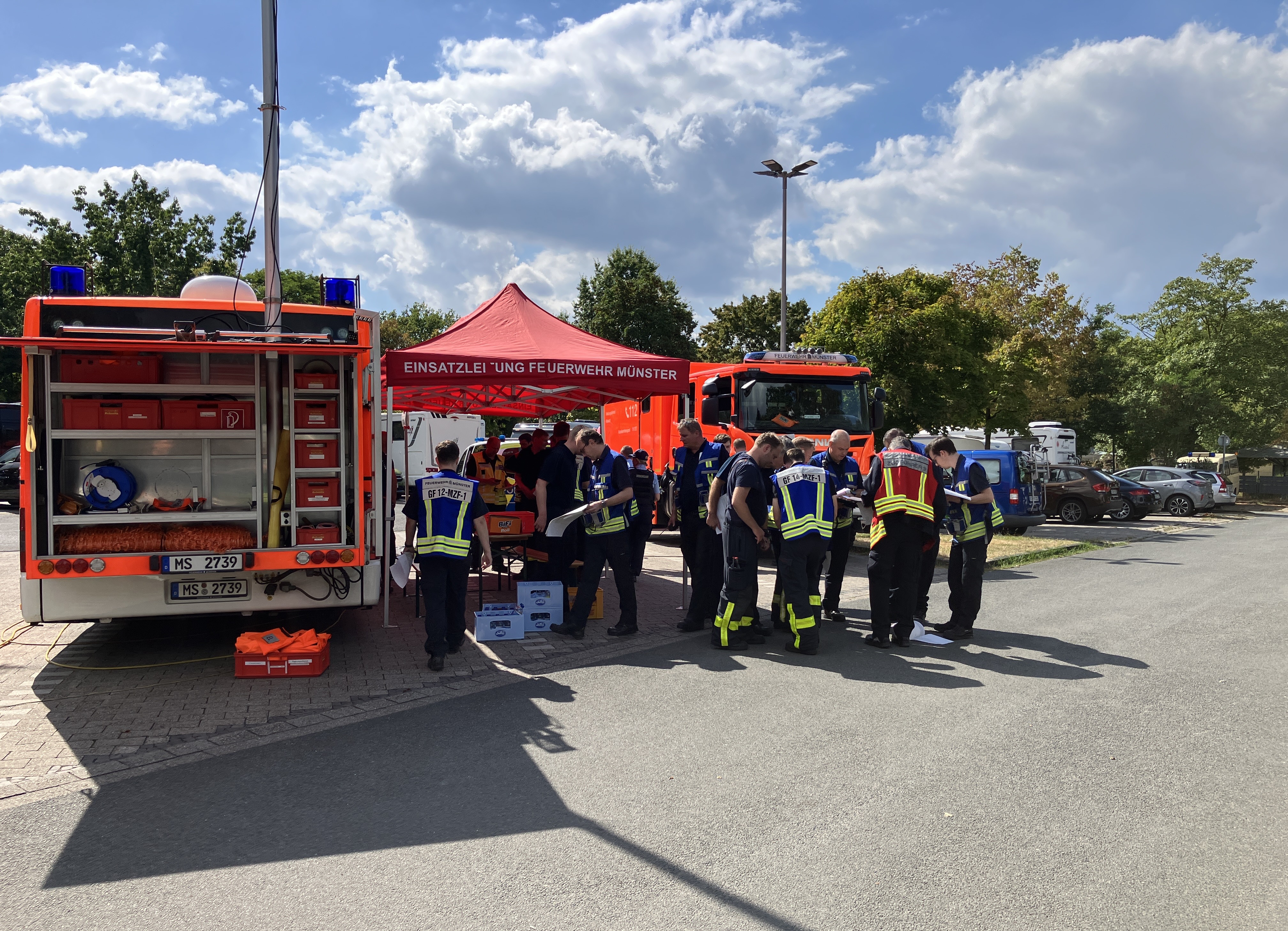Team der Feuerwehr neben einem Einsatzfahrzeug auf einem Parkplatz