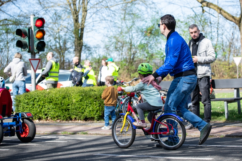 Ein Kind fährt auf einem kleinen Fahrrad und wird dabei angeschoben.