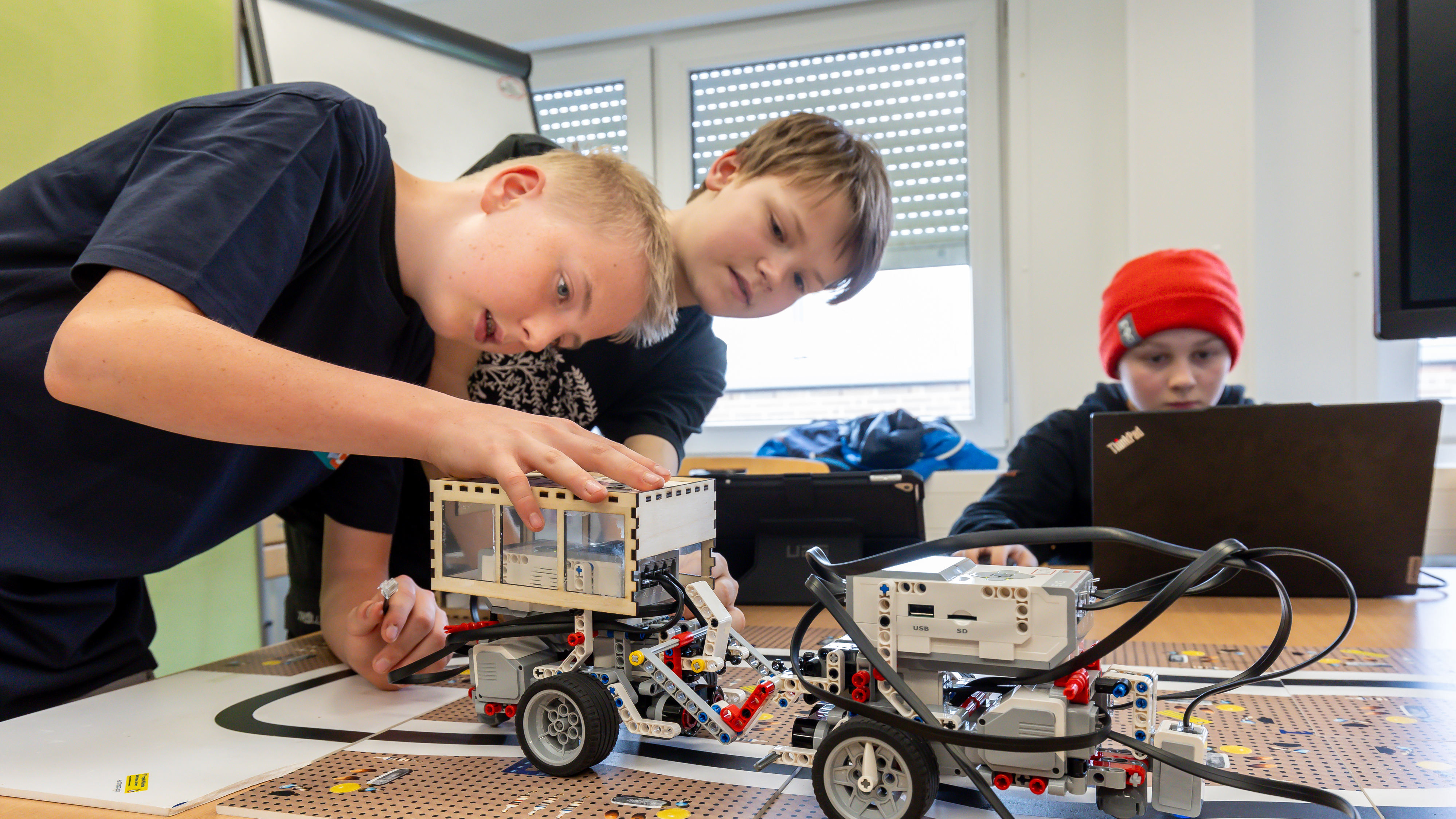 3 Jungs arbeiten an einem Lego Bus