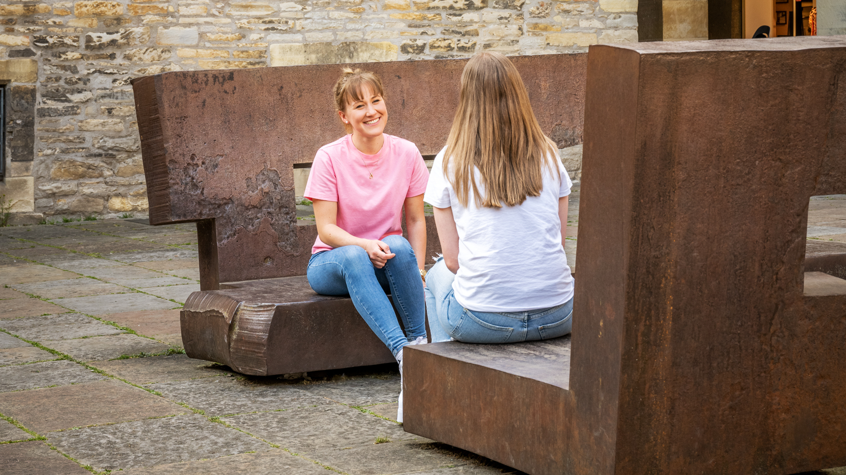 Zwei Personen sitzen auf den Chillida-Bänken im Rathausinnenhof