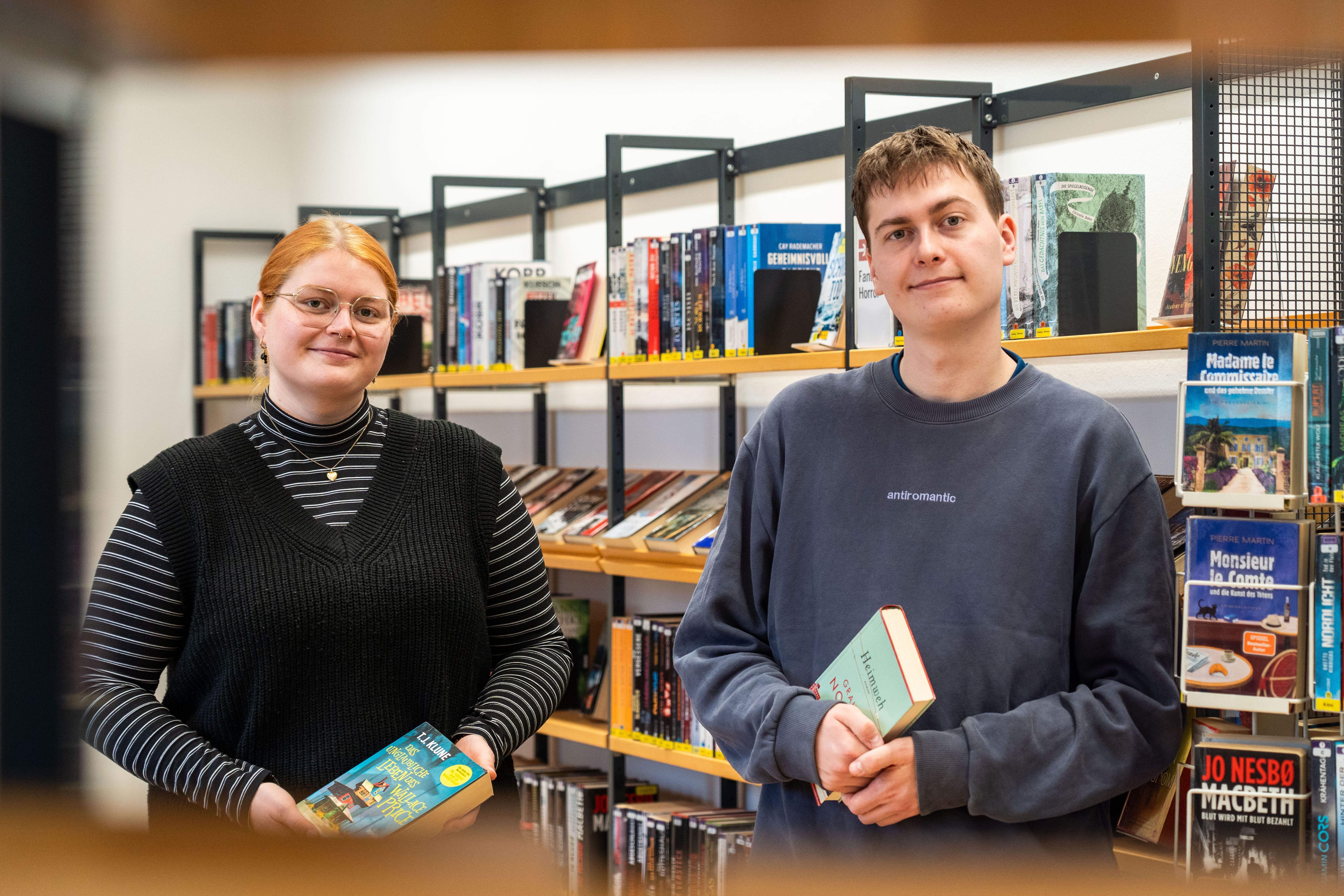 Zwei Auszubildende vor einem Bücherregal