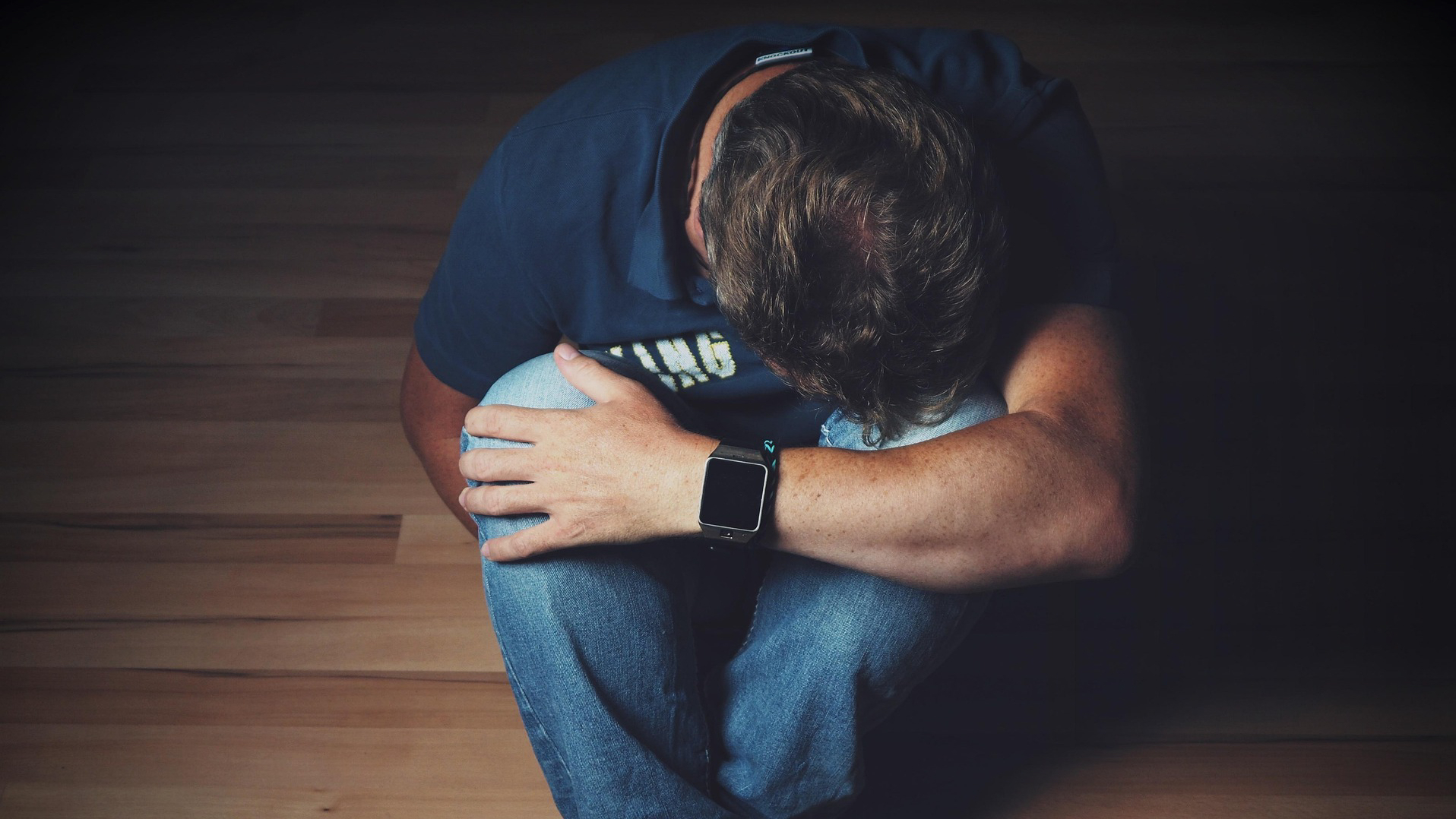 Mann sitzt auf dem Boden und trauert