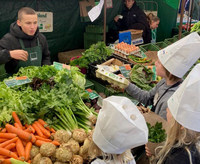 Die Spachtel-Leeze ist erstmals auf dem Geistmarkt im Einsatz Kinder mit Kochmütze auf dem Markt vor Gemüsestand