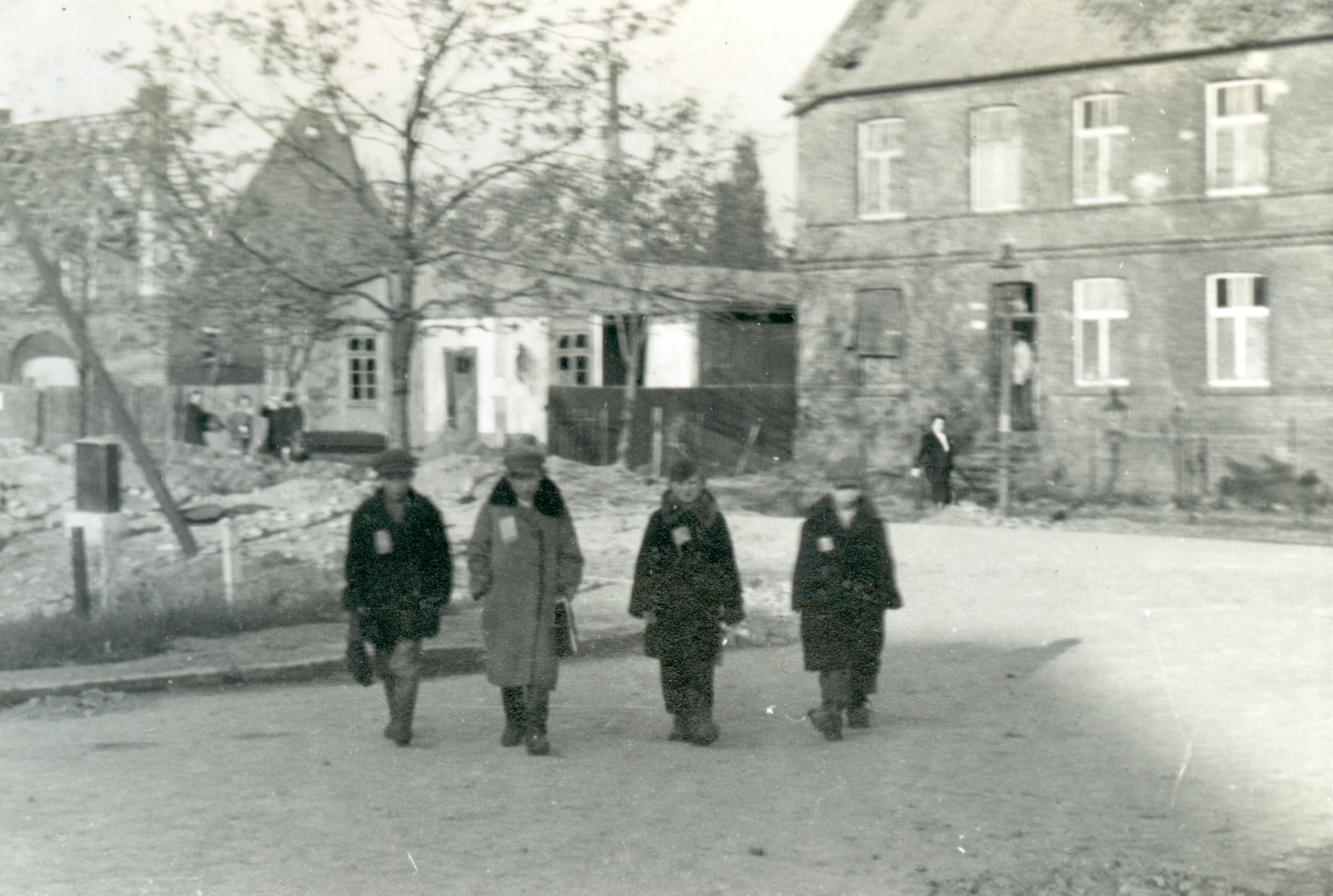 Vier Kinder stehen auf einem Platz und machen sich auf den Weg zur Trümmerräumung