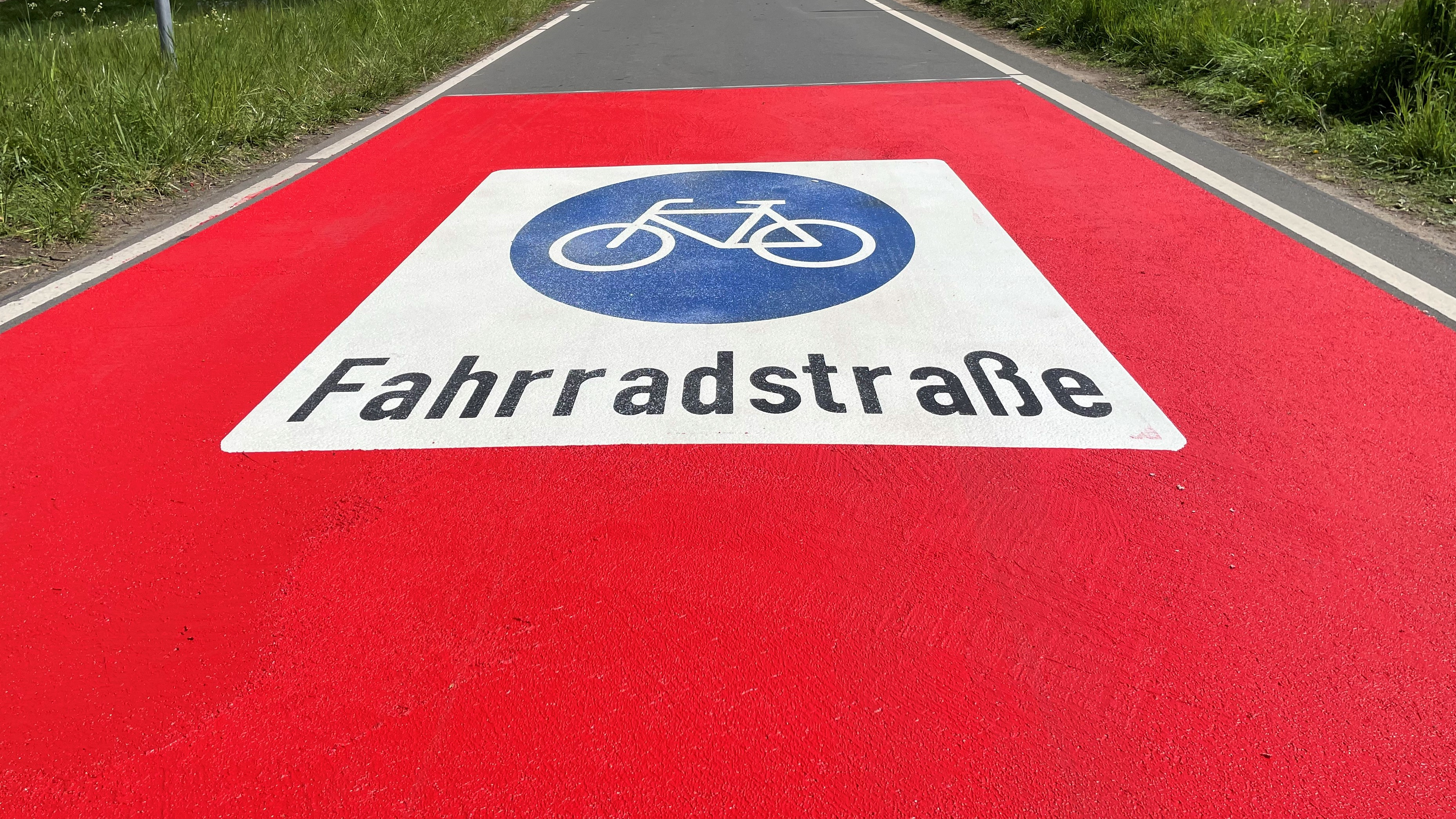 Blick auf die Kötterstraße mit Fahrradicon und rotem Asphalt am Anfang der Straße