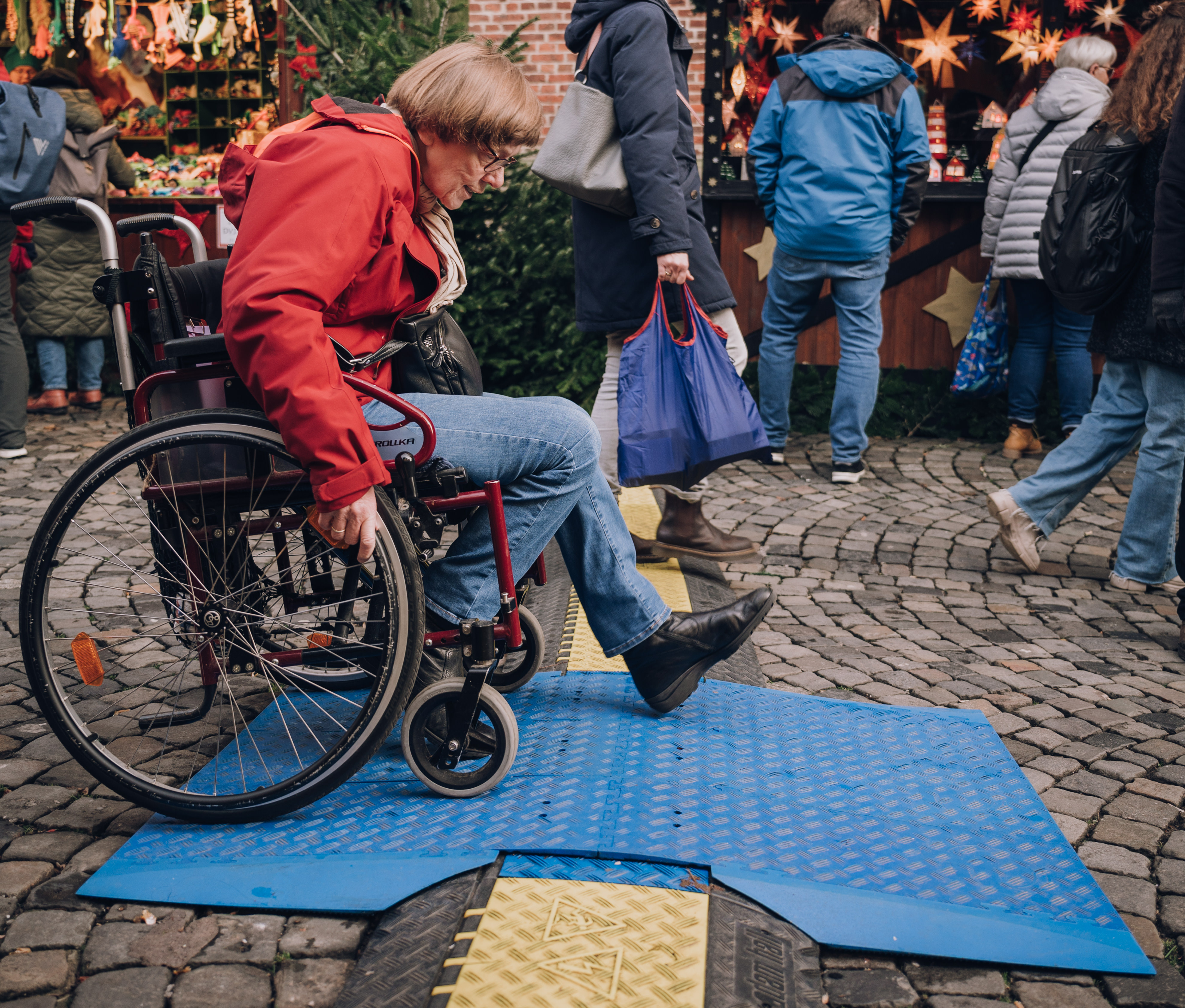 Diese Kabelbrücke auf dem Weihnachtsmarkt in der Salzstraße ist in der Mitte mit einer Brücke mit geringer Steigung ausgestattet und deswegen für Rollstuhlfahrer einfacher zu überqueren.