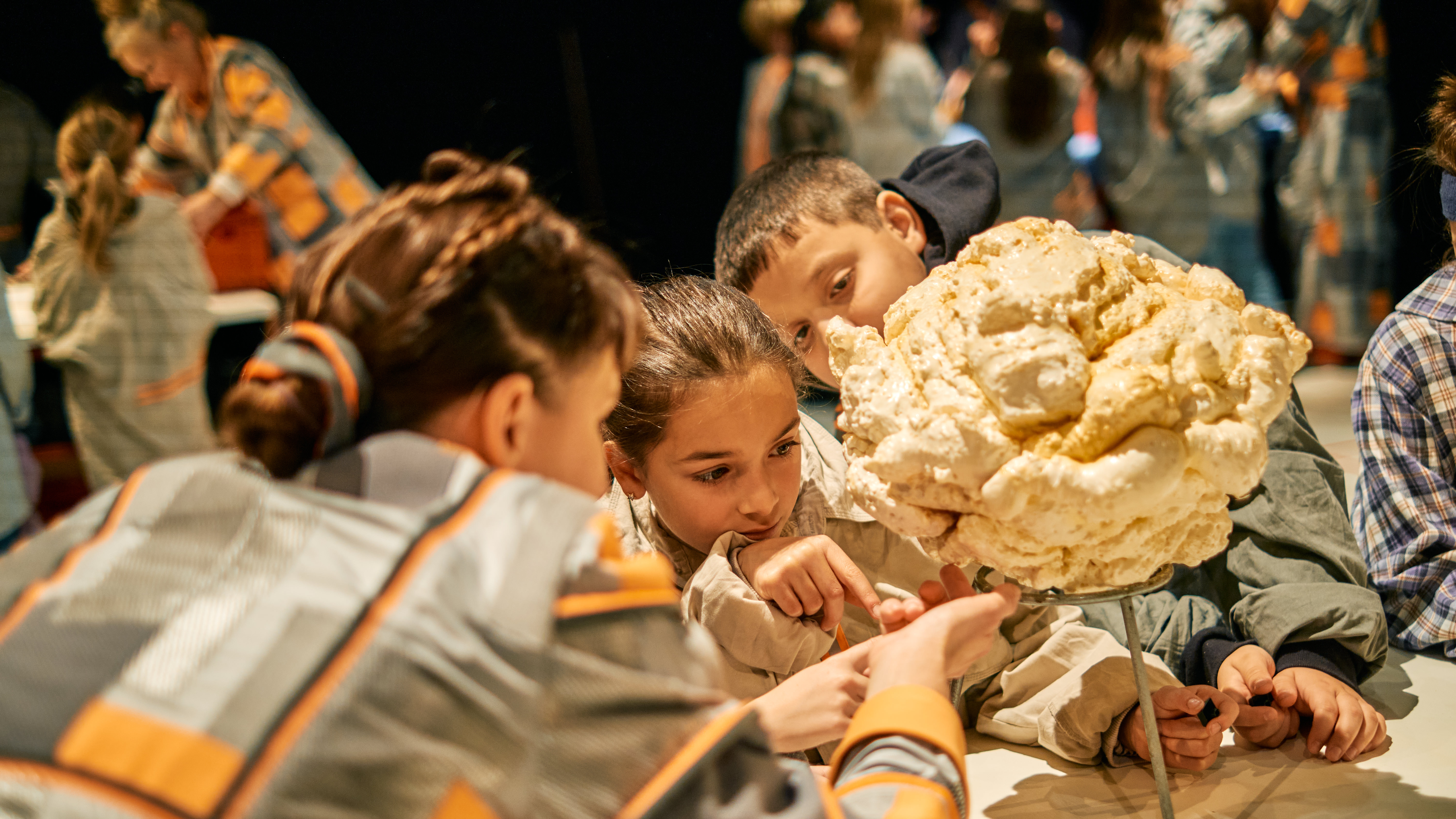 Eine Gruppe von Kindern schaut interessiert auf ein großes Model eines Popcorns.