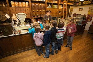 Sieben Kinder stehen vor einer historischen Ladentheke und spielen das Einkaufen