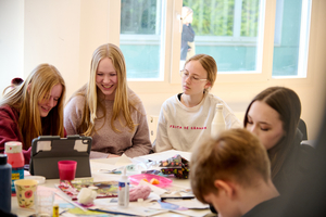 Gruppenfoto: fünf Jugendliche sitzen am Tisch und zeichnen