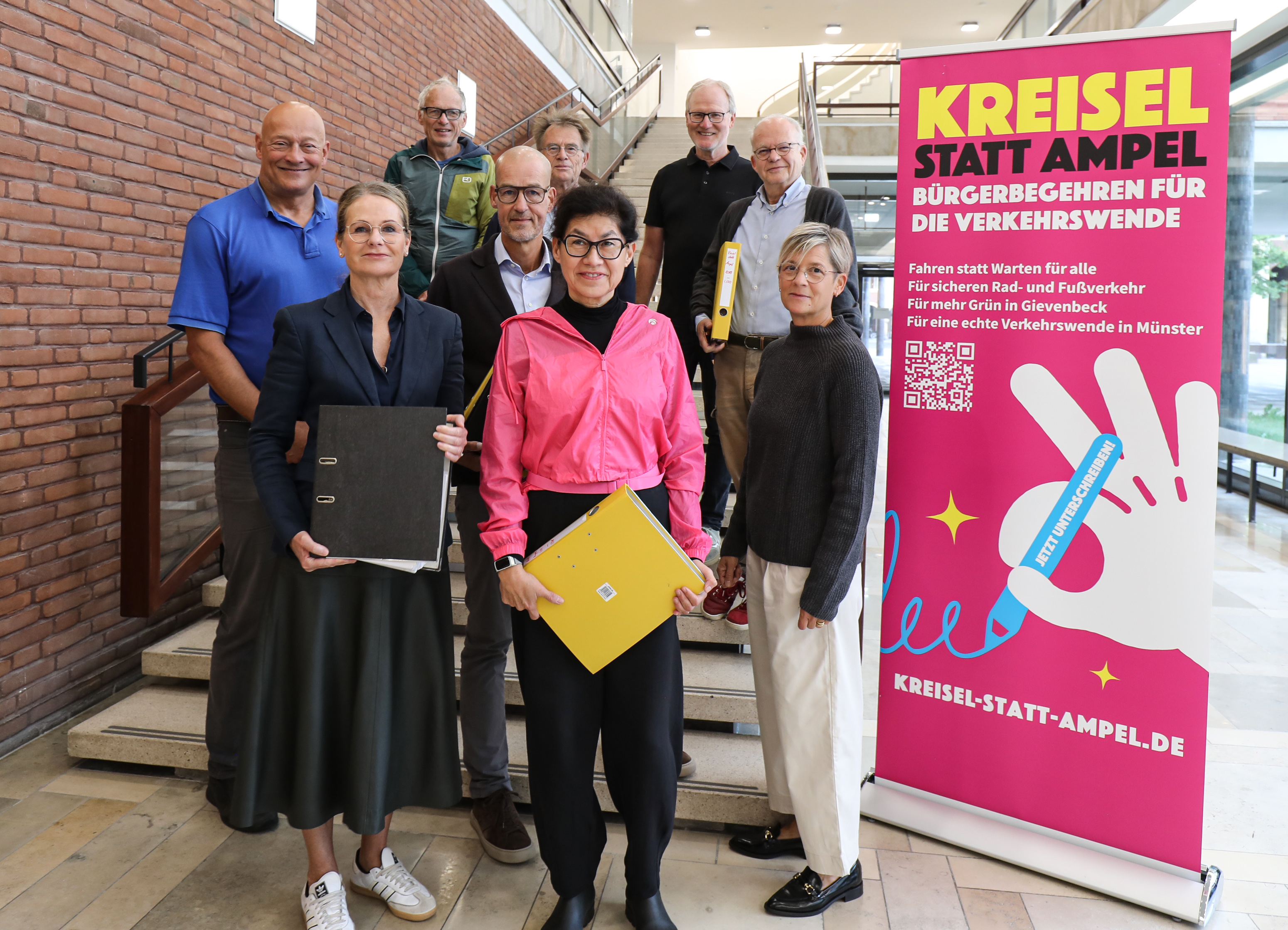 Neun PErsonen neben einem großen Banner mit der Aufschrift "Kreisel statt Ampel"