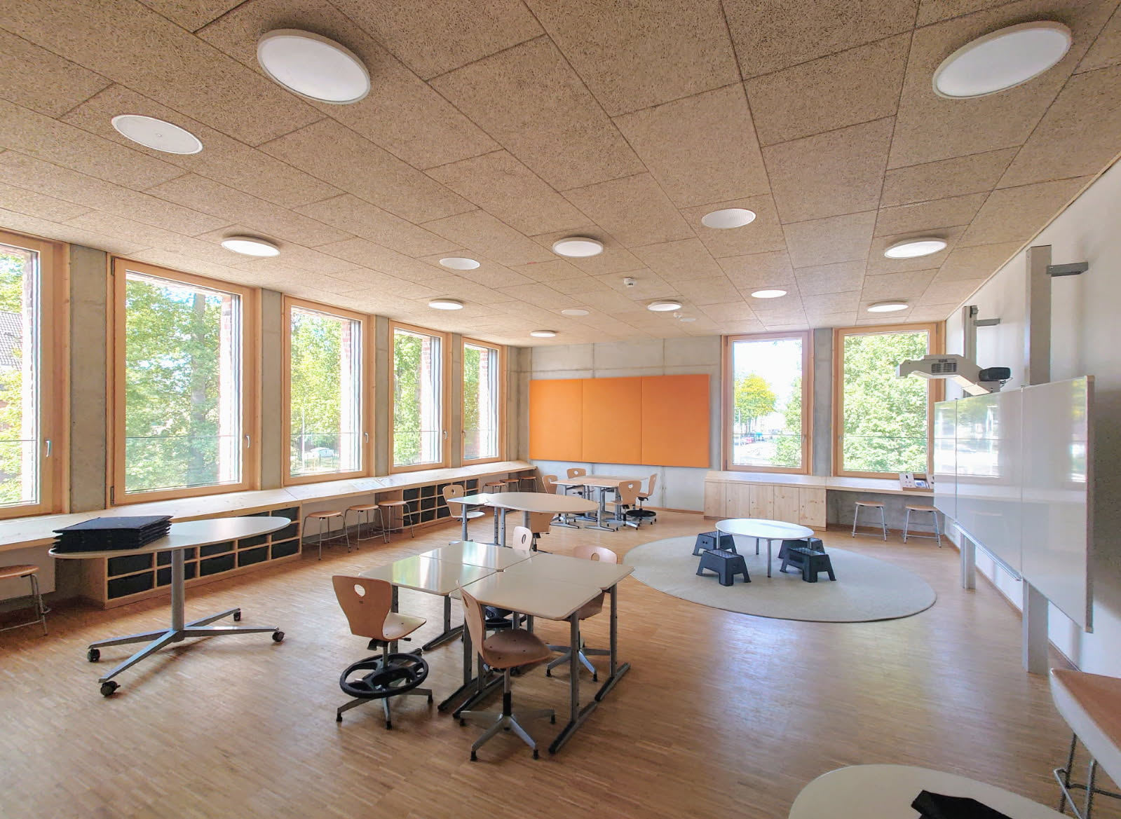 Blick in den Klassenraum mit Tischen, Stühlen und großen Fenstern