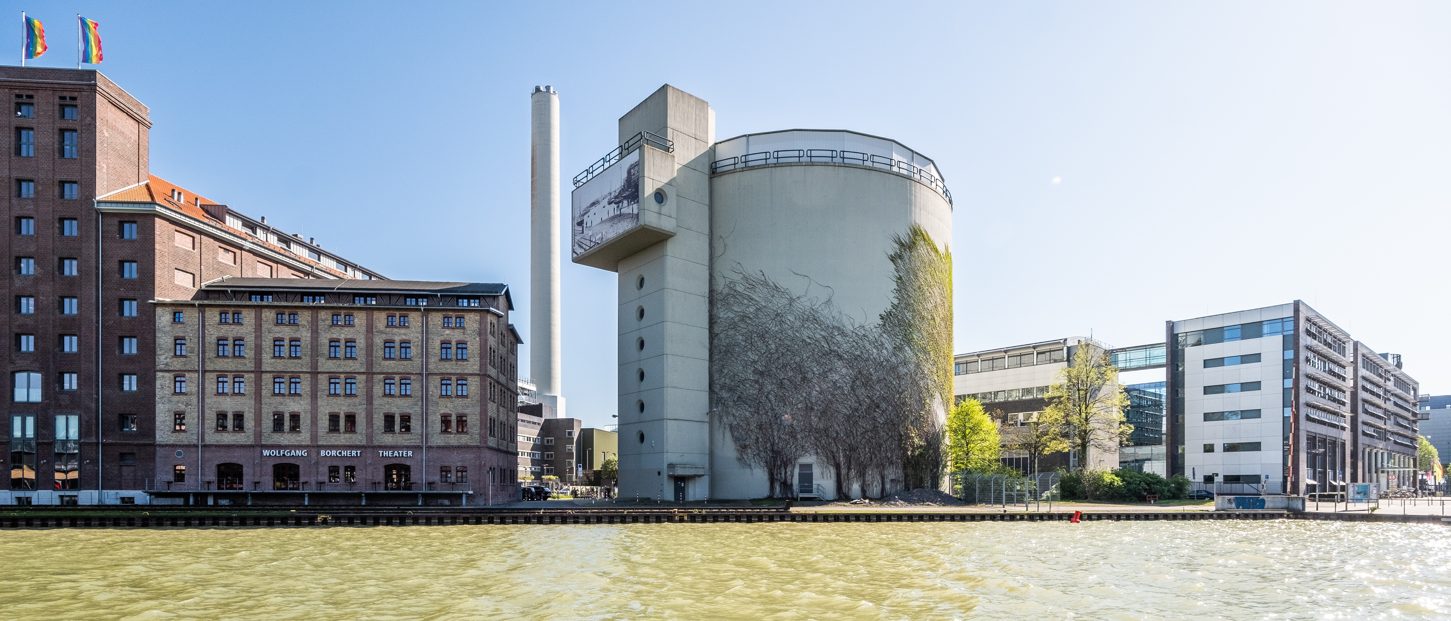 Blick über das Wasser auf einen Warmwasserspeicher in Form eines großen Betonrundbaus