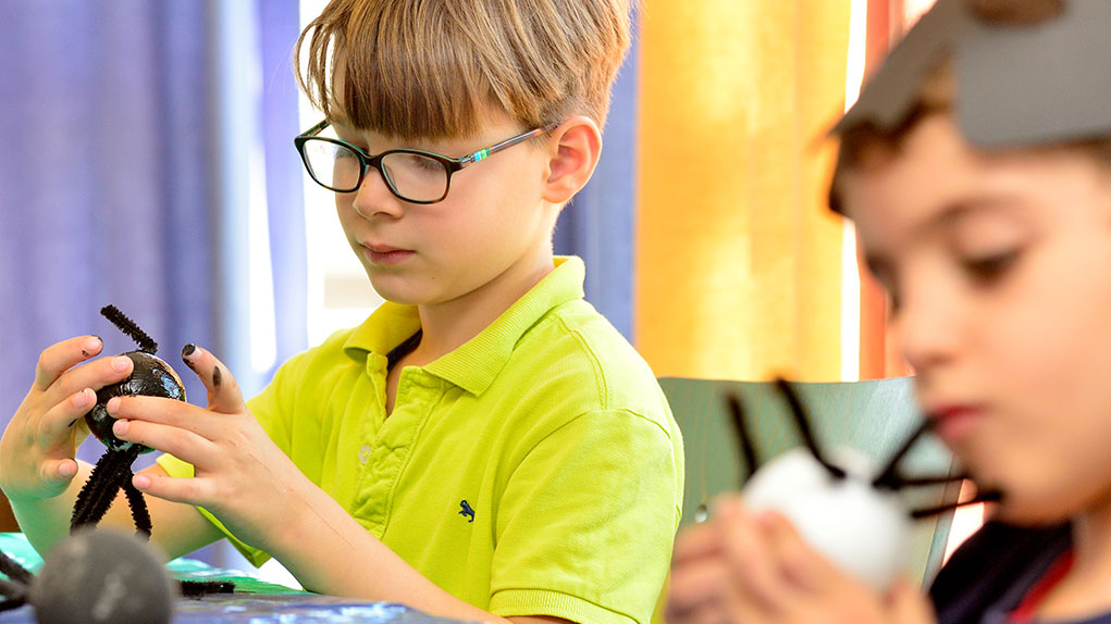 Zwei Kinder sitzen am Tisch und basteln