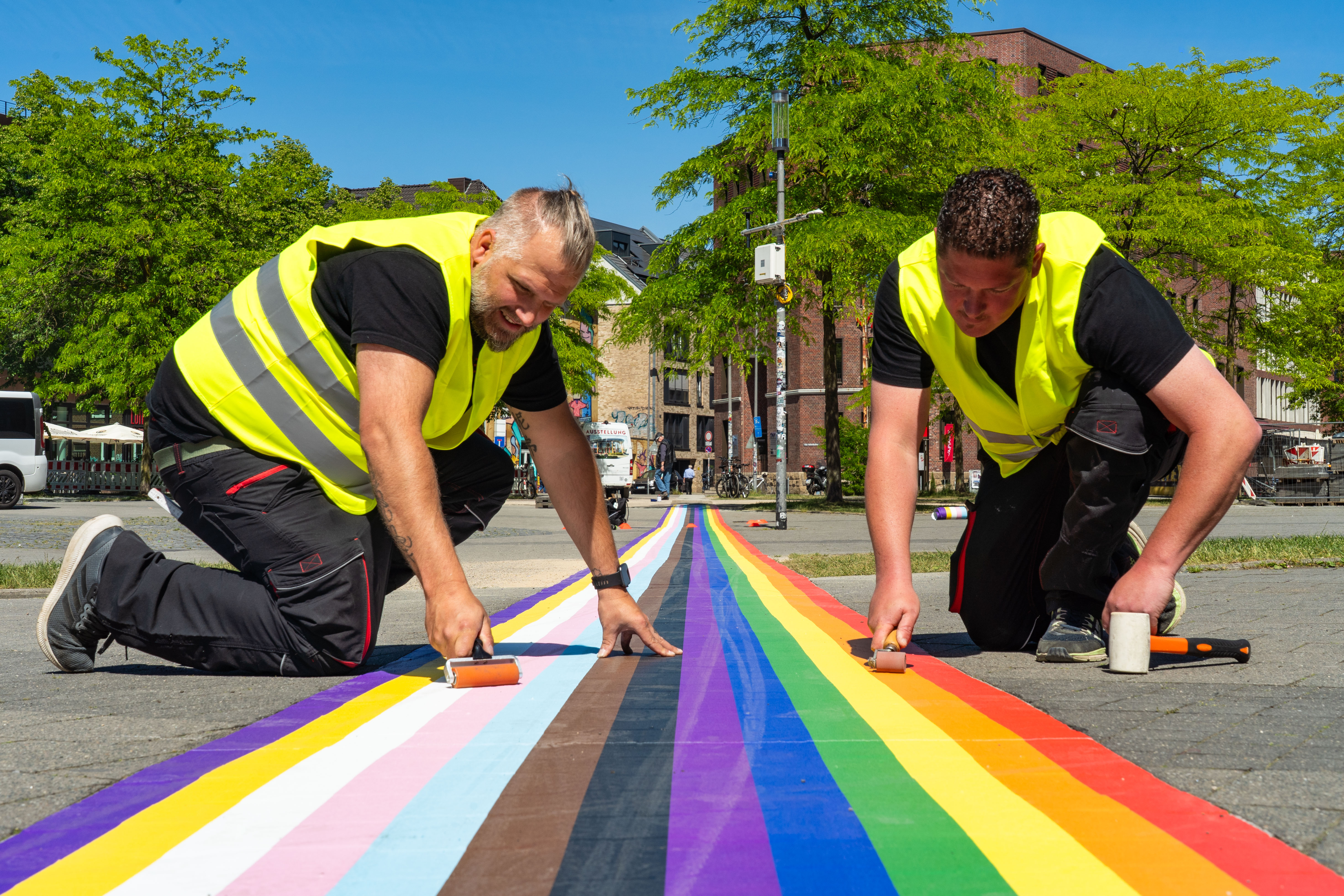 Mitarbeiter einer Spezialfirma, die den Regenbogenstreifen auf dem Hafenplatz anbringen