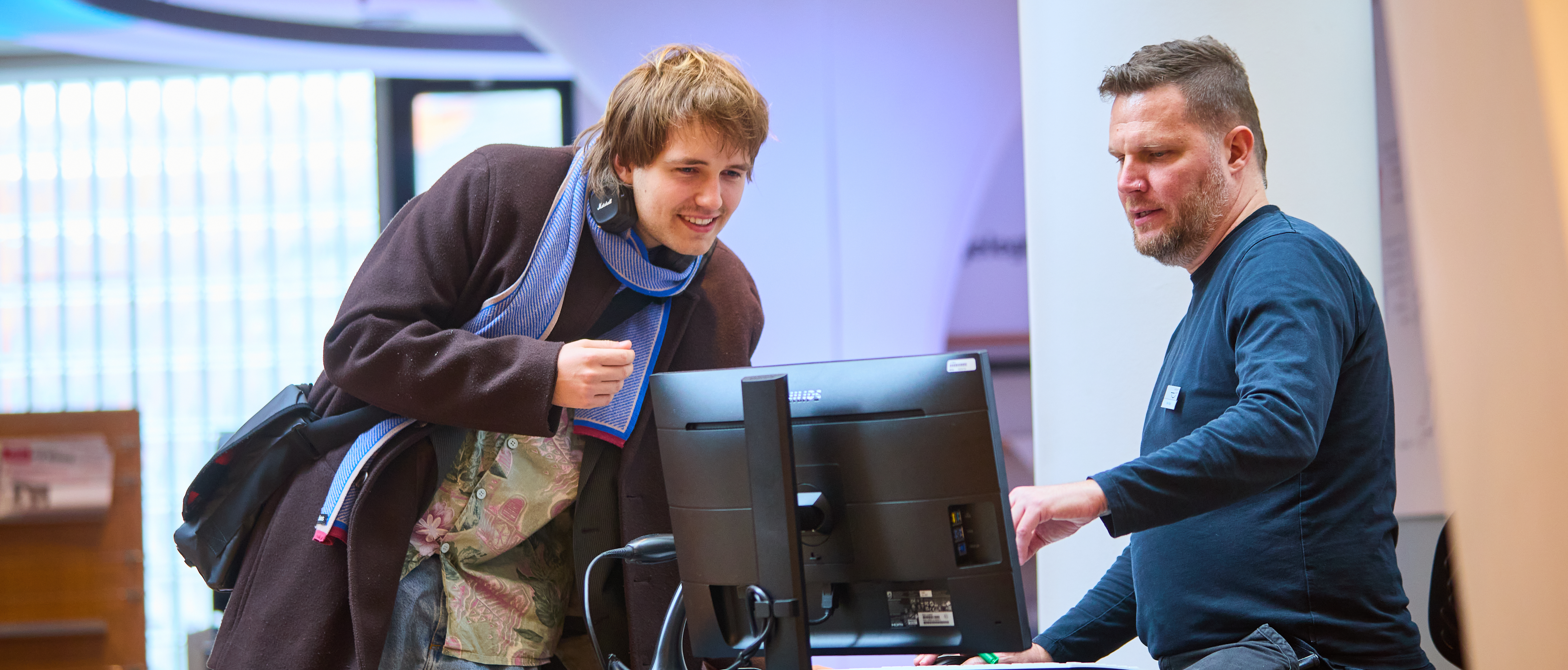 Beratungssituation: ZWei Männer stehen vor einem Computer