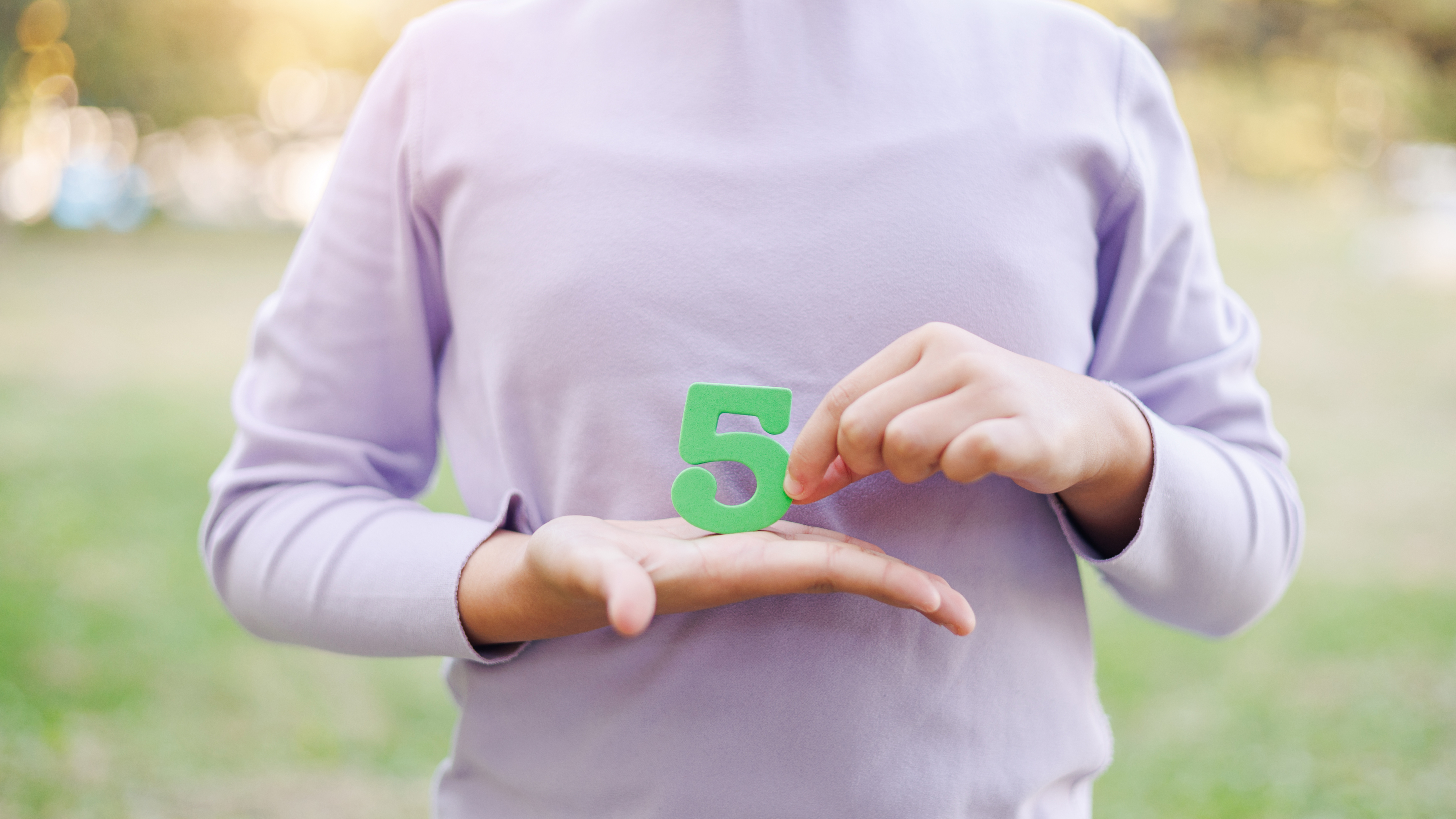 Frau mit einer 5 in der Hand