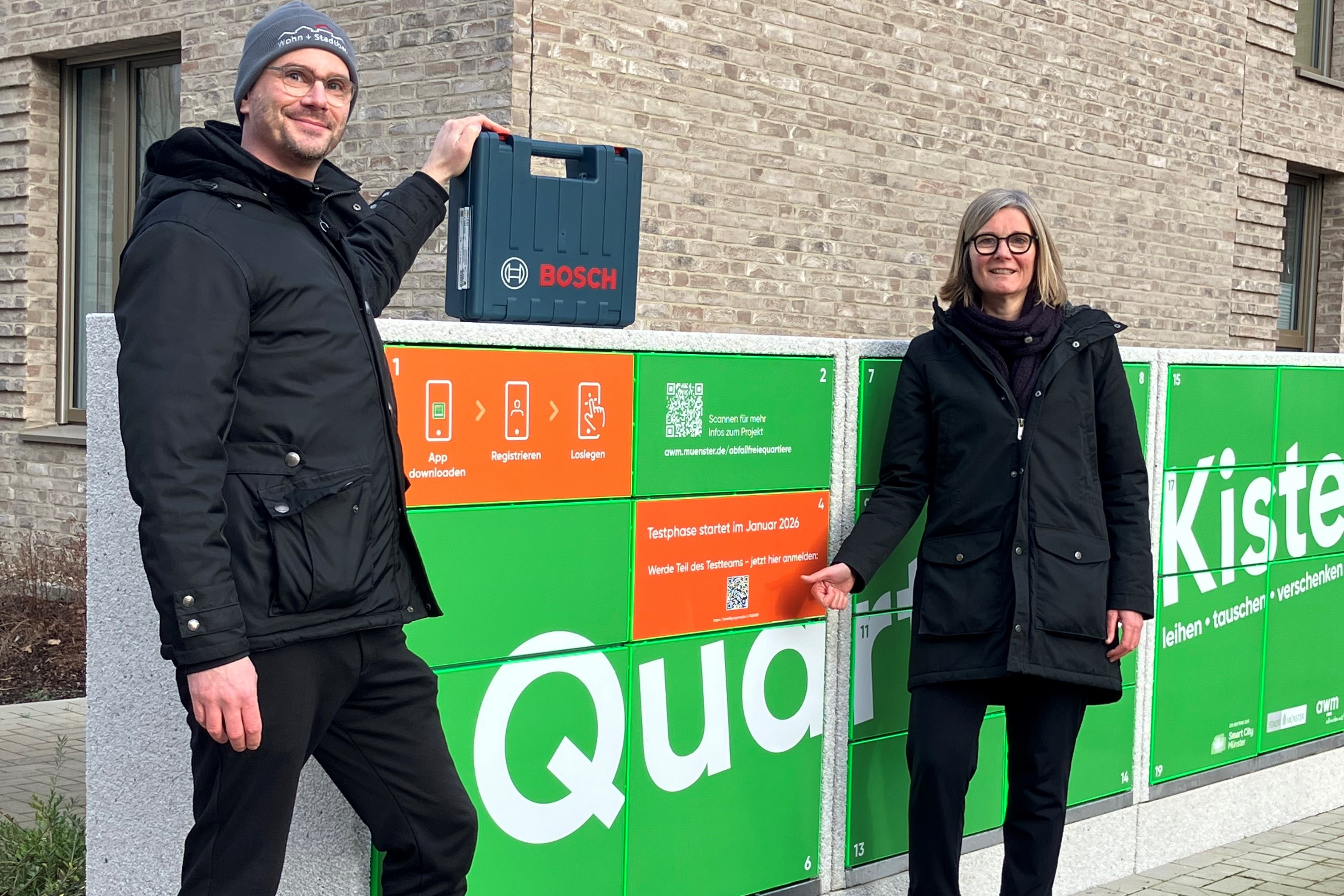 Vinzenz Heidrich (Wohn+Stadtbau, Quartiersmanager York) und Stefanie Heeke (awm, Projektleitung SmartWaste) vor der Quartierskiste im York Quartier
