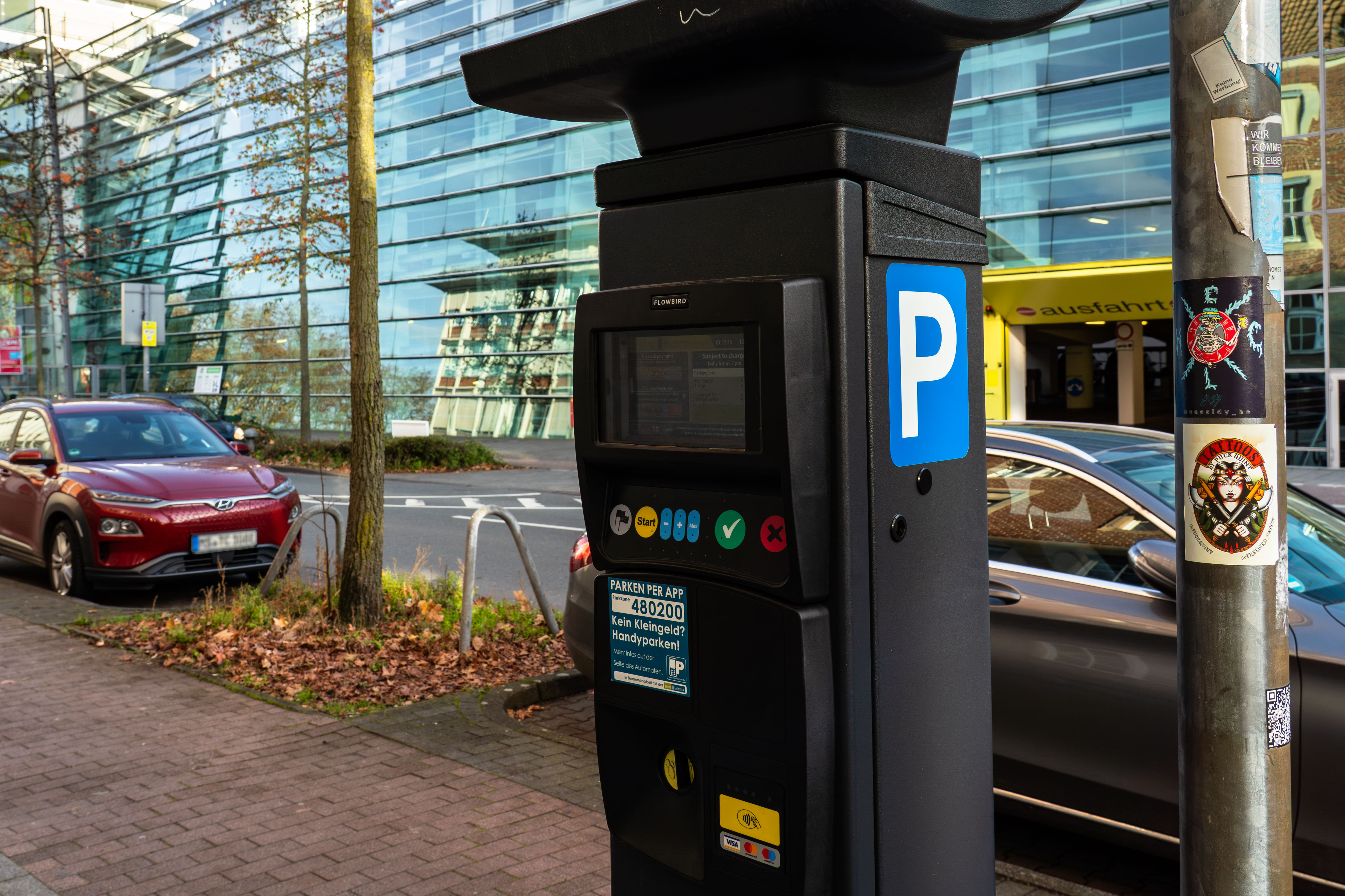 Parkautomat mit Autos im Hintergrund