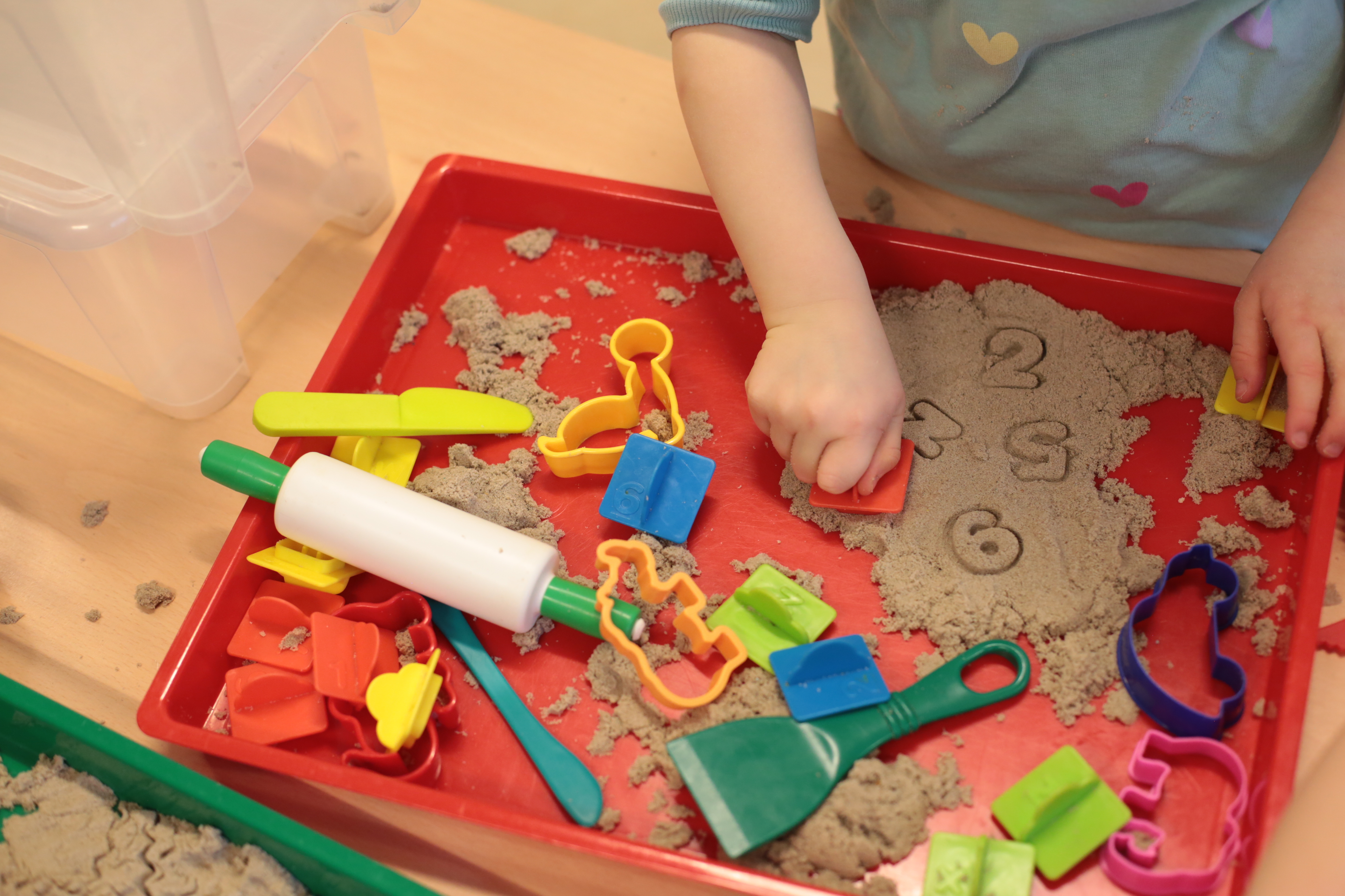 Kleines Kind spielt mit Ausstechförmchen und Sand