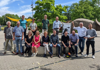 Gemeinsam zu erfolgreichen Lösungen kommen: Das deutsch-niederländische Projektteam „Wasserrobuste Städte“. 6 Personen sitzen auf einer Betonmauer und  8 andere Personen haben sich daneben oder dahinter positioniert.