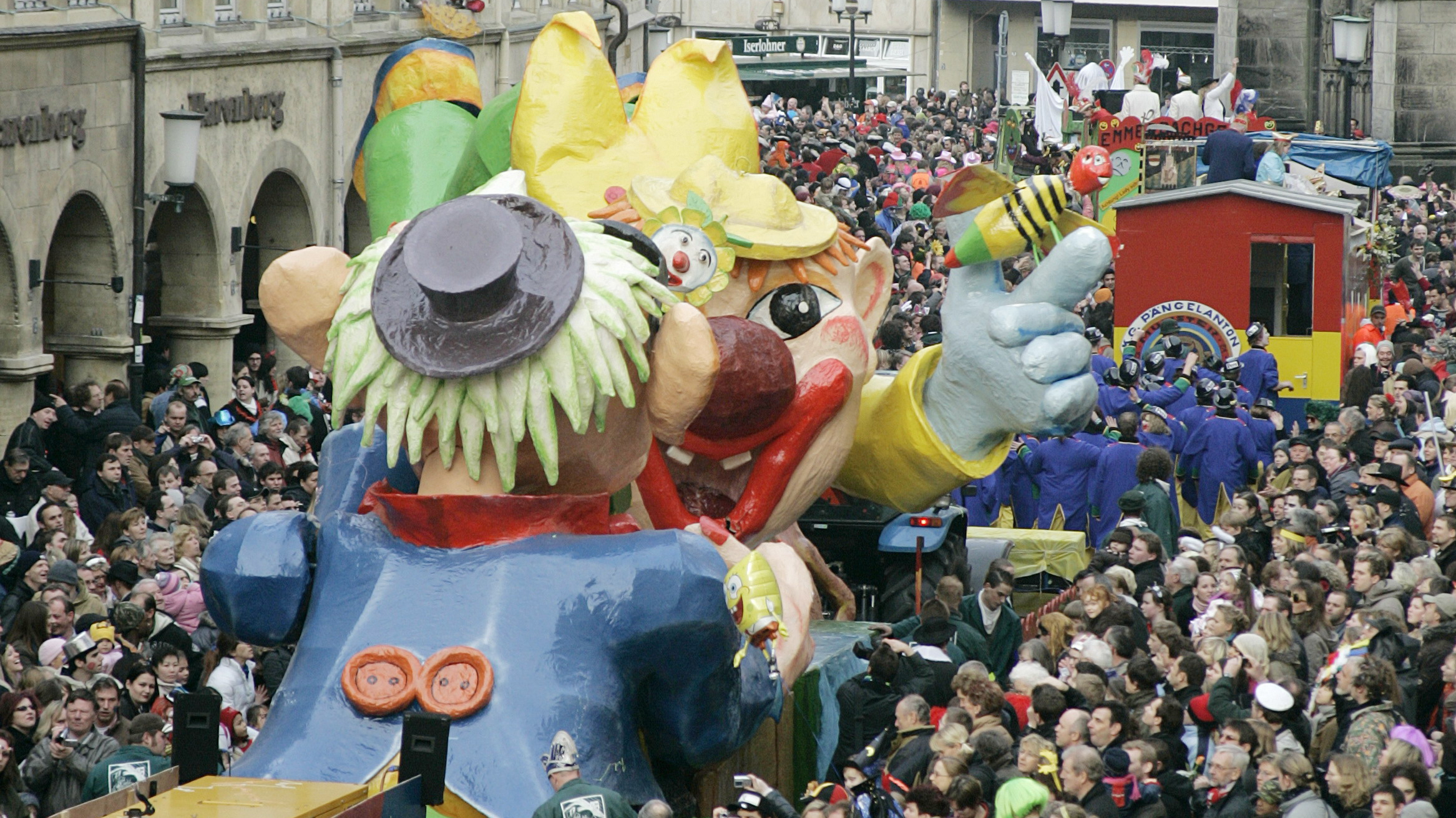 Beim Rosenmontagszug in Münster drängen sich große bunte Wagen und Zuschauende auf dem Prinzipalmarkt.