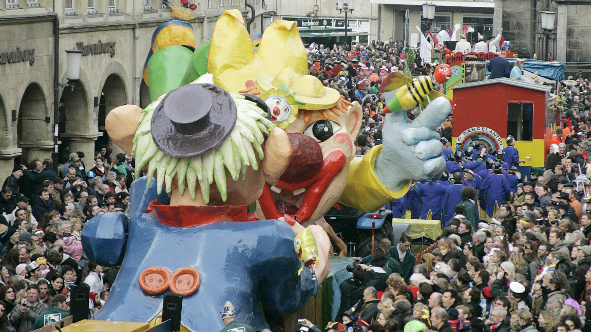 Beim Rosenmontagszug in Münster drängen sich große bunte Wagen und Zuschauende auf dem Prinzipalmarkt.