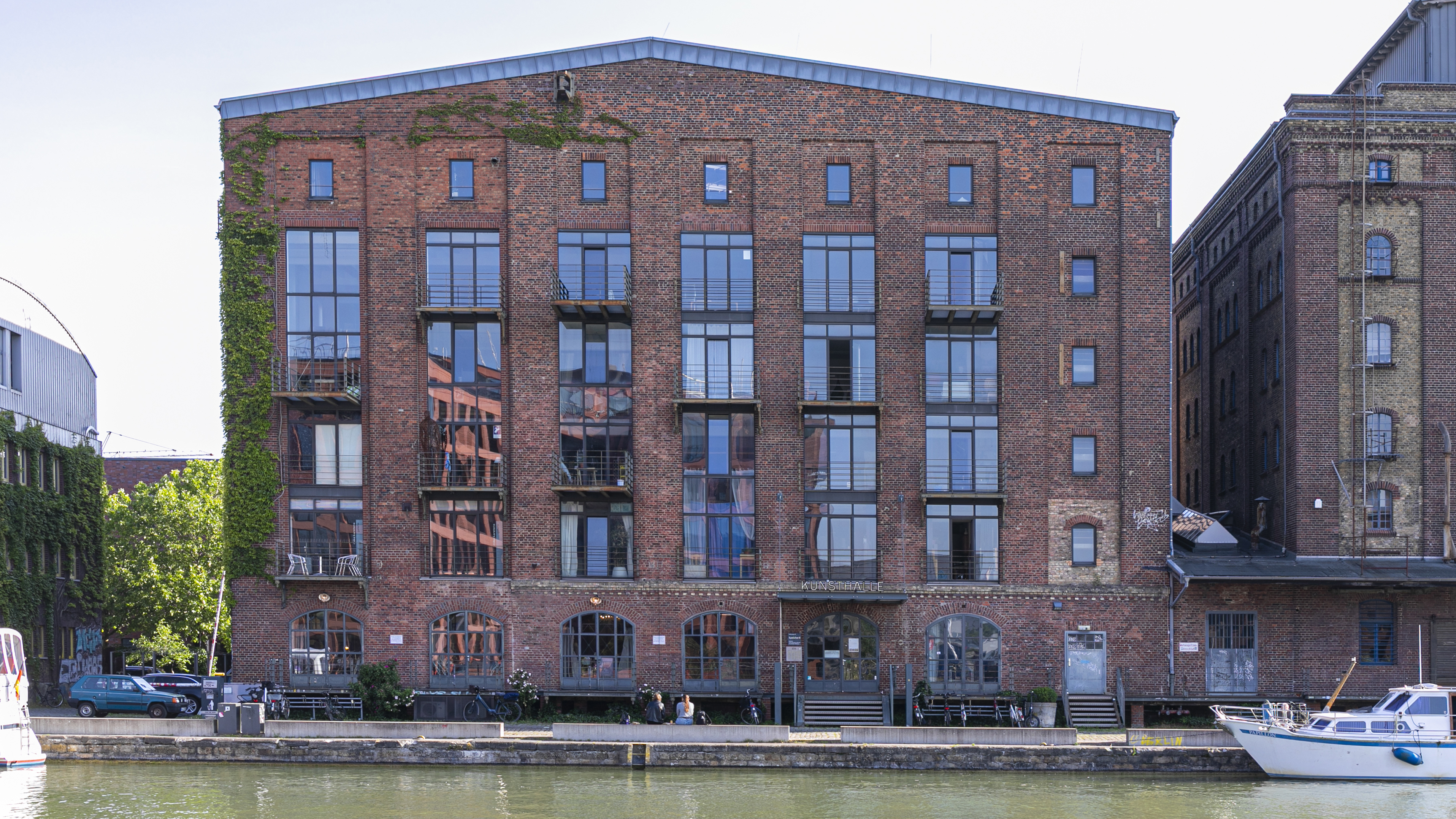 Großes rotes Backsteingebäude von außen mit Kanal davor
