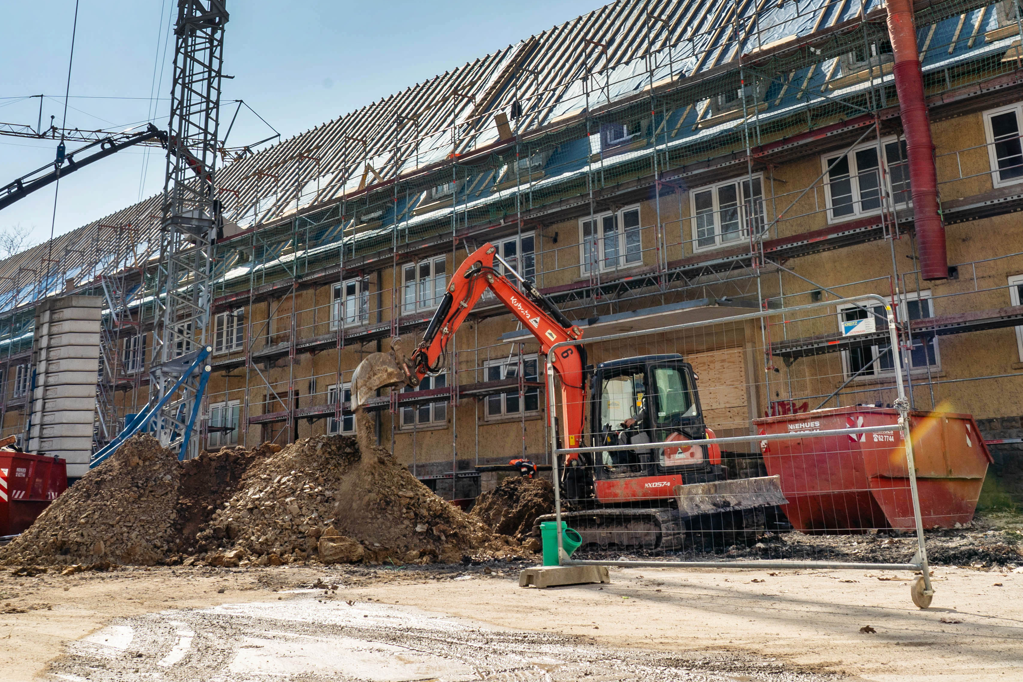 Blick auf die Baustelle des Gebäudes mit Baukran, Bagger, LKW und Baugerüst