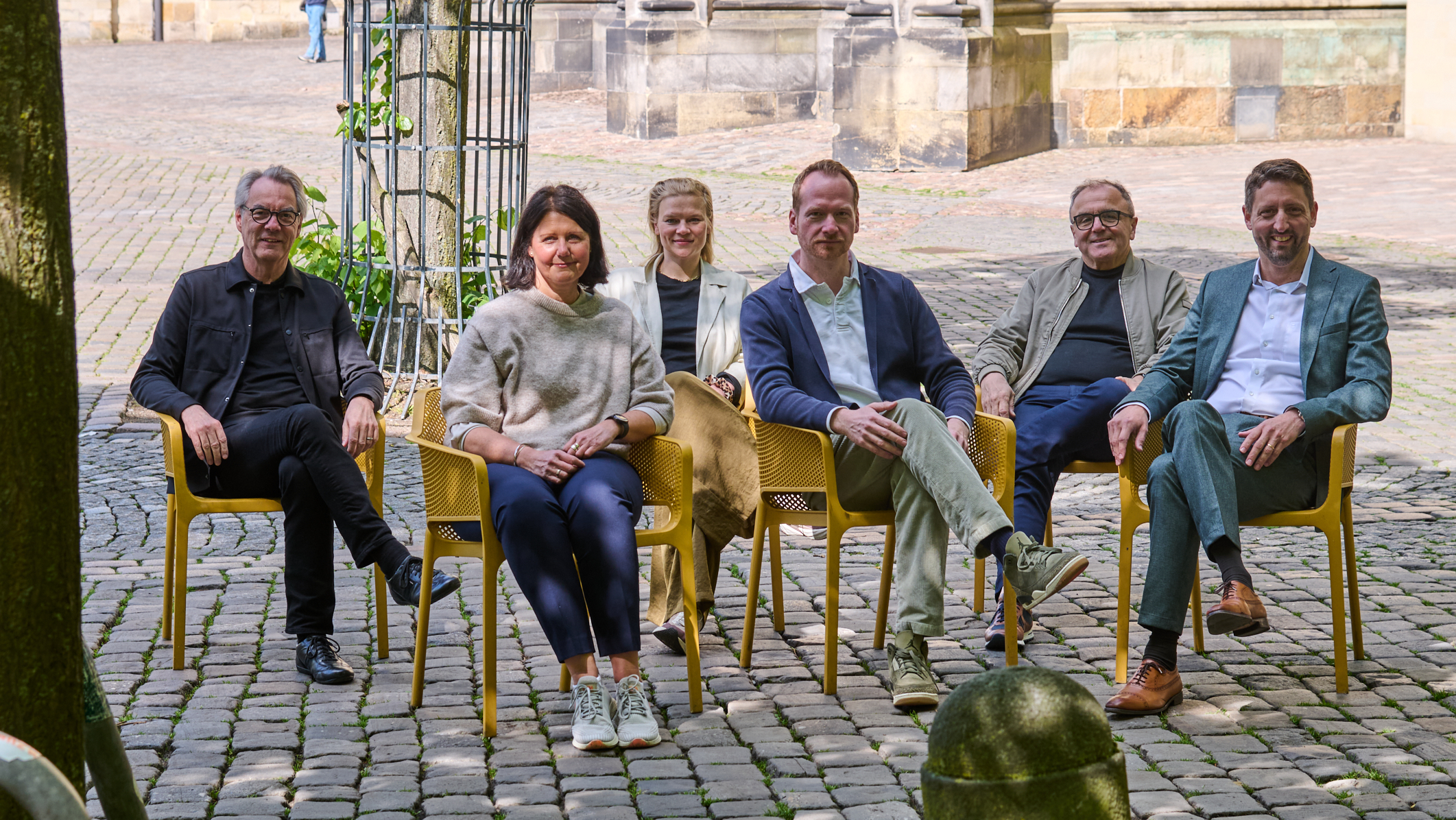 Vertreter von Stadt und ISI sitzen auf den gelben Stühlen auf dem Domplatz