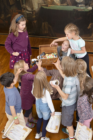 Kinder freuen sich über die gefundene Schatztruhe im Stadtmuseum. Die Truhe ist geöffnet und voller Süßigkeiten.