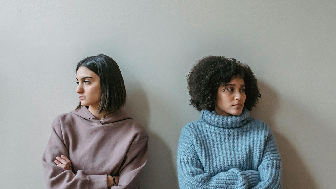 Zwei Frauen schweigen nach einem Streit und schauen voneinander weg.