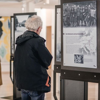 Menschen sehen sich in einem Foyer Ausstellungstafeln an.