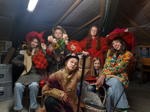 Das junge Ensemble ‚Meerwiesel‘ sitzt als Gruppe hintereinander und schaut in die Kamera. Alle sind verkleidet, manche mit manche ohne Hüte.