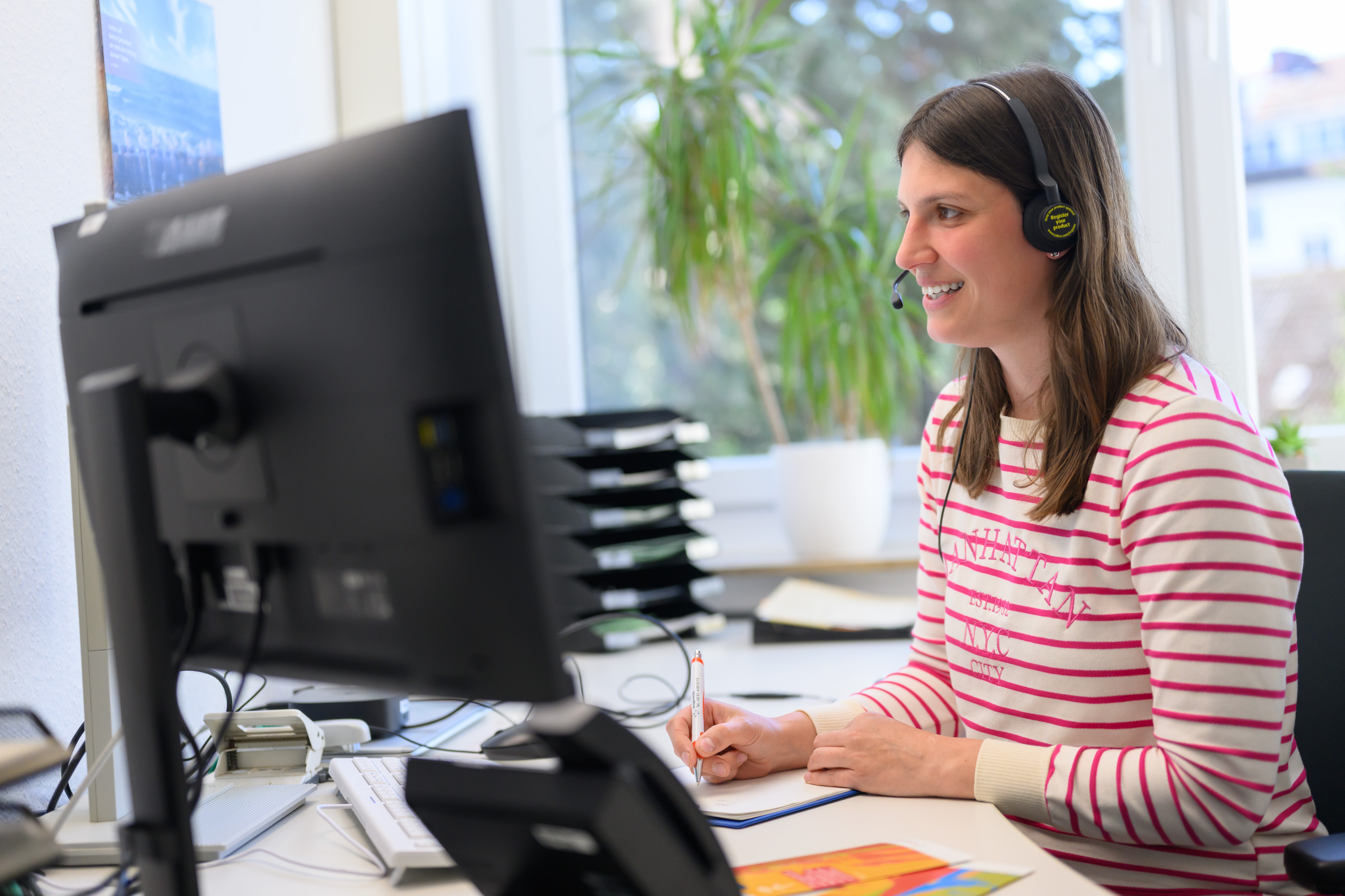 Die ausgebildete Fachkraft der städtischen Drogenhilfe sitzt hinter dem PC und hat ein Headset auf.