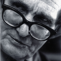 Ein Porträtfoto von Paul Wulf. Er schaut zur Seite, den Kopf leicht schief gelegt, seine Brille liegt relativ weit unten auf seiner Nase auf