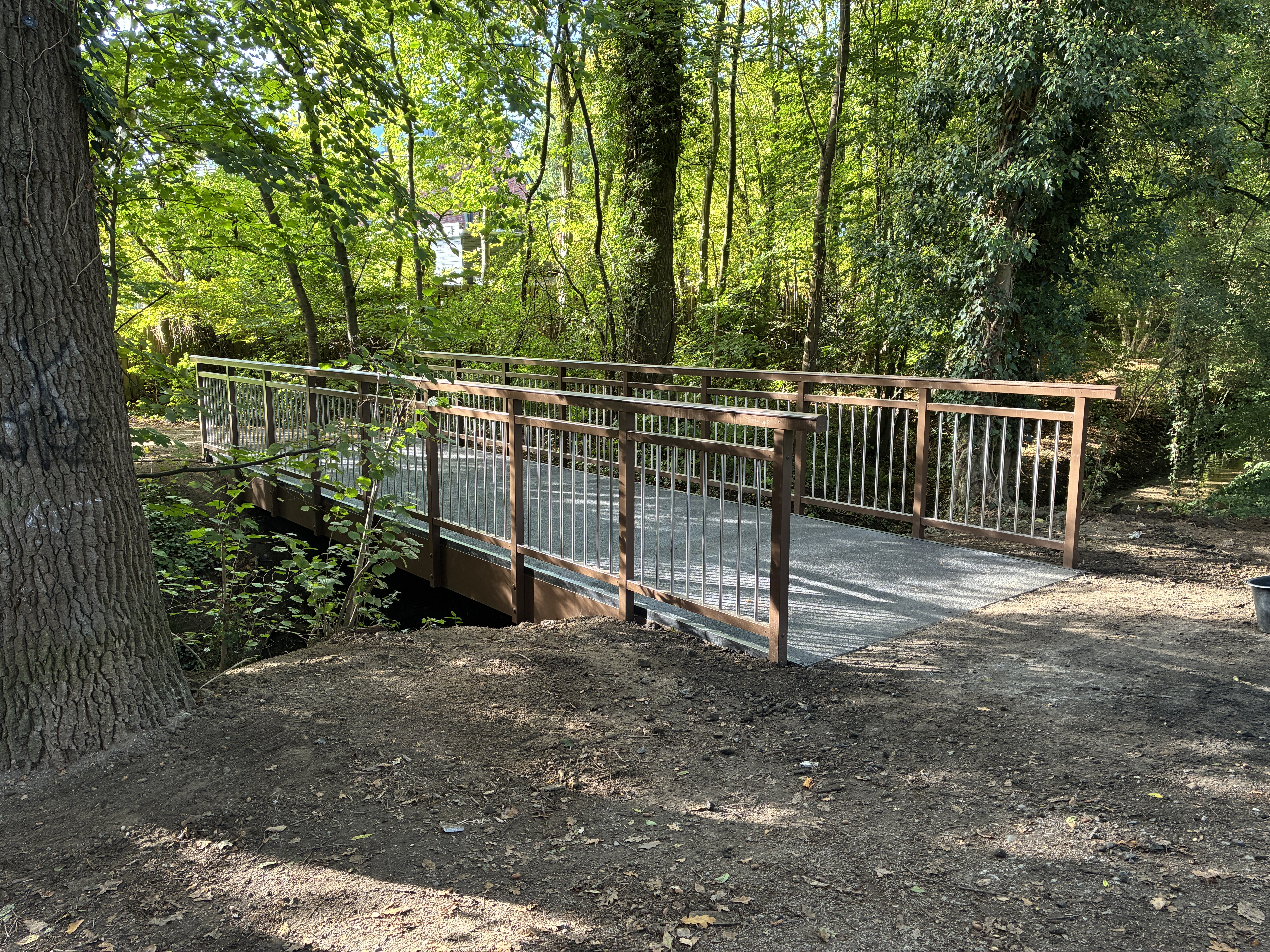 Eine Holzbrücke führt über einen Bach im Wald
