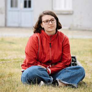 junge Frau sitzt in Schneidersitz auf dem Gelände der KZ-Gedenkstätte Sachsenhausen