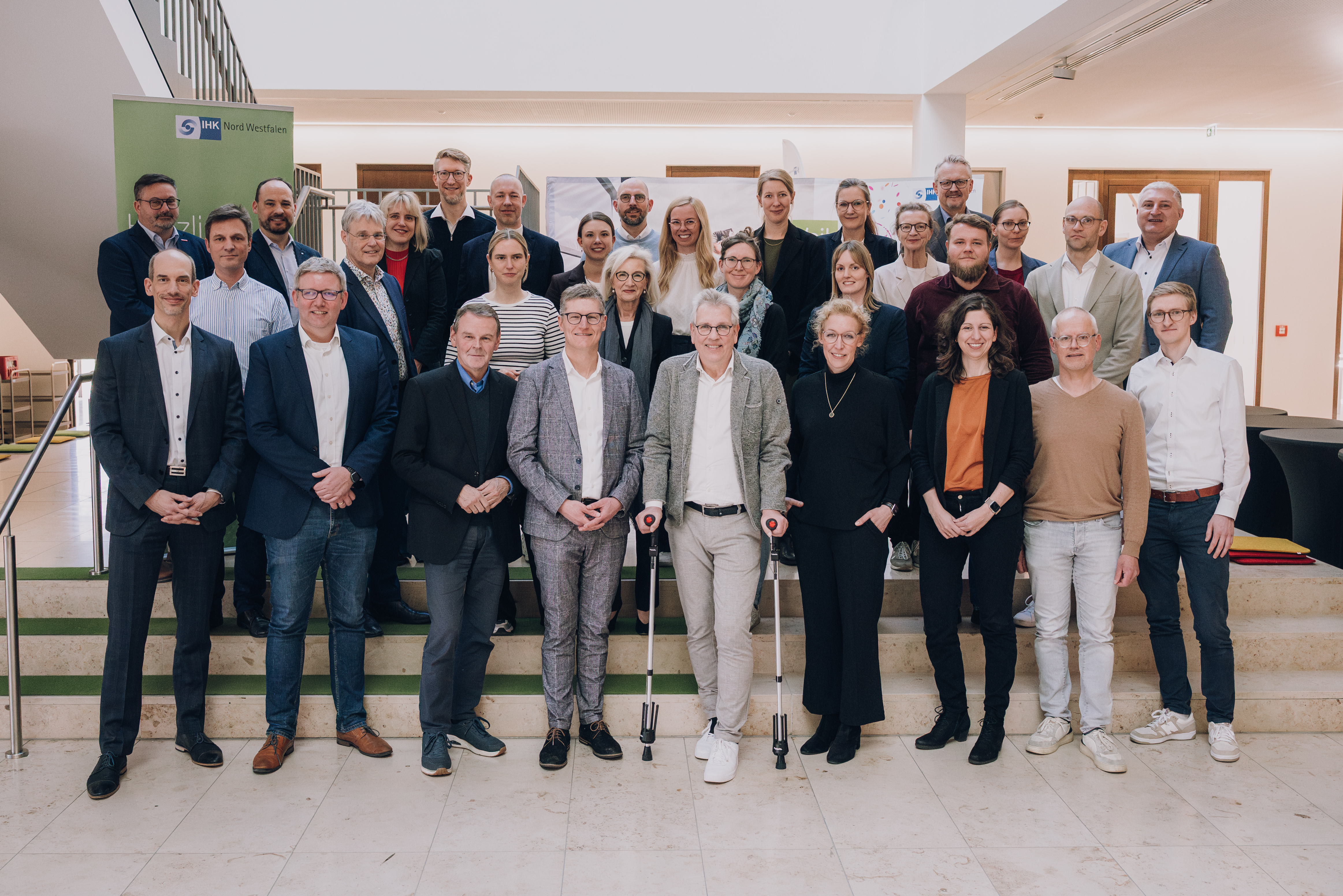 Gruppenfoto mit vielen Personen in heller Halle vor großer Treppe. Oberbürgermeister Tilman Fuchs vorne 4.v.l., tauschte sich mit Vertreterinnen und Vertretern aus Wirtschaft und Wissenschaft aus. 